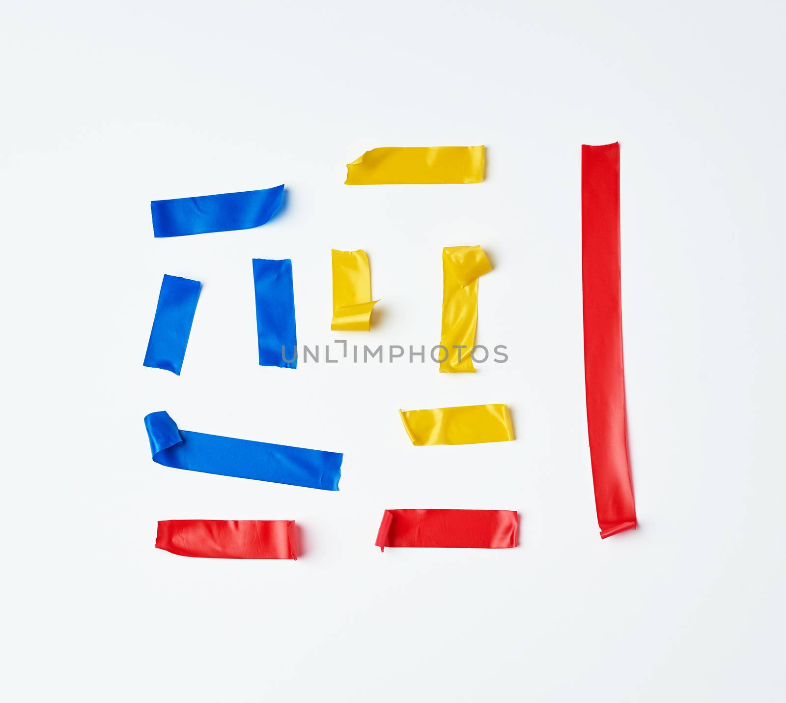 set of torn multicolored rubber pieces of electrical tape glued to a white background, close up