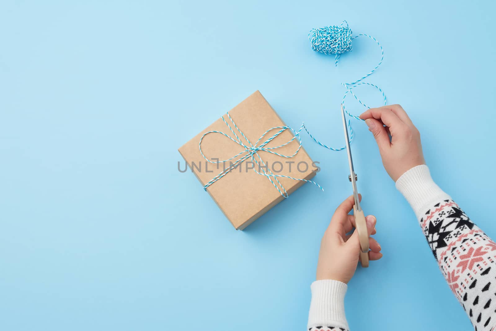 gift wrapped and tied with a brown rope, female hand with scissors cuts a brown rope, congratulation concept, copy space