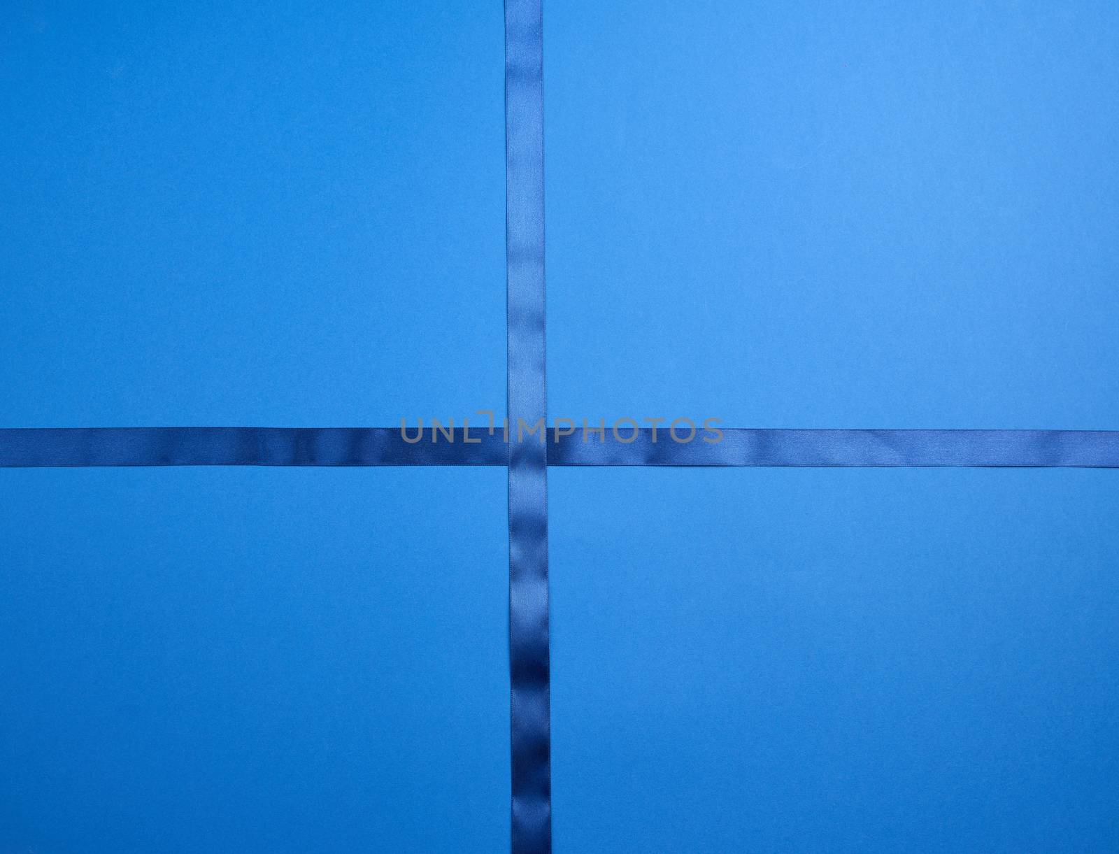 blue silk ribbon crossed on a dark blue background, imitation of tying a gift, top view