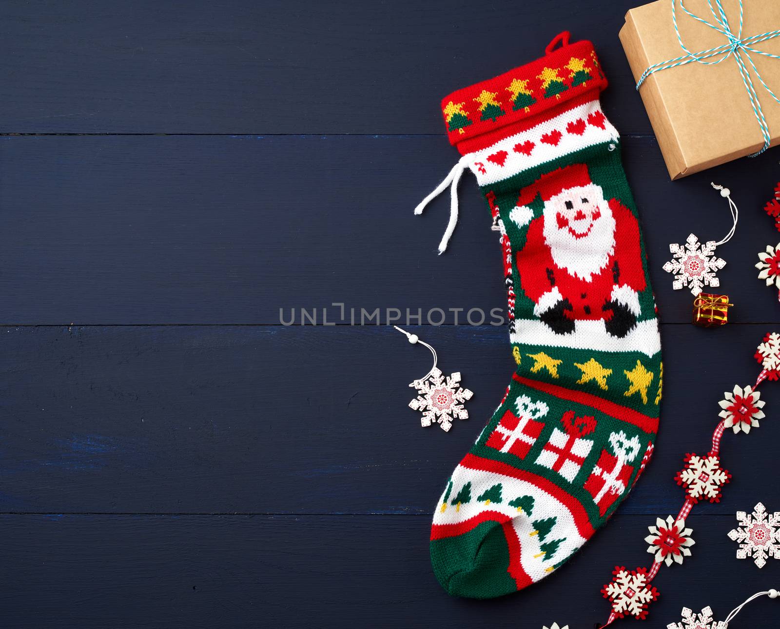 bright knitted christmas sock and decor on a blue wooden background from boards. Christmas decoration background, copy space