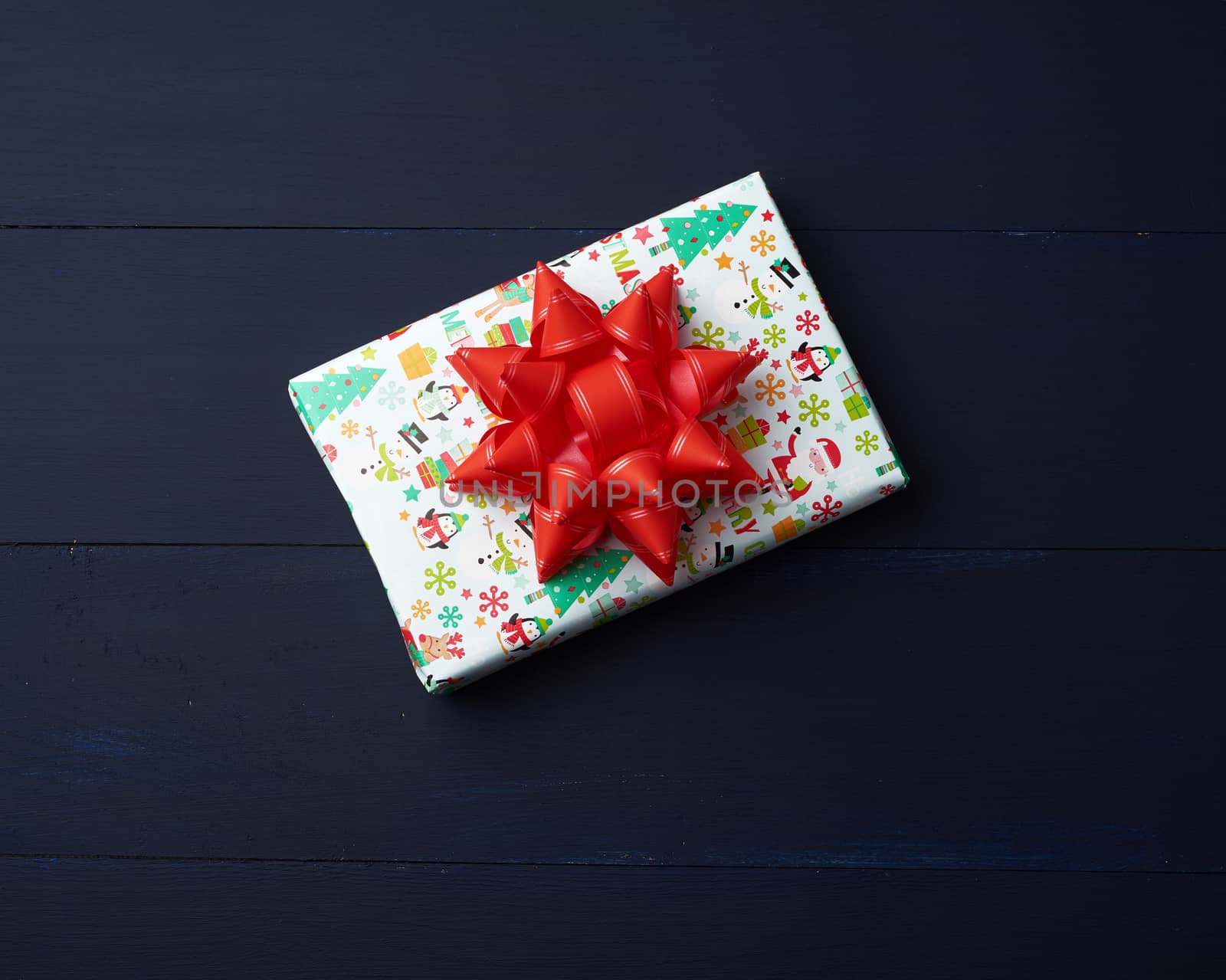 gift wrapped in multi-colored paper on a blue wooden background, festive backdrop, top view, copy space