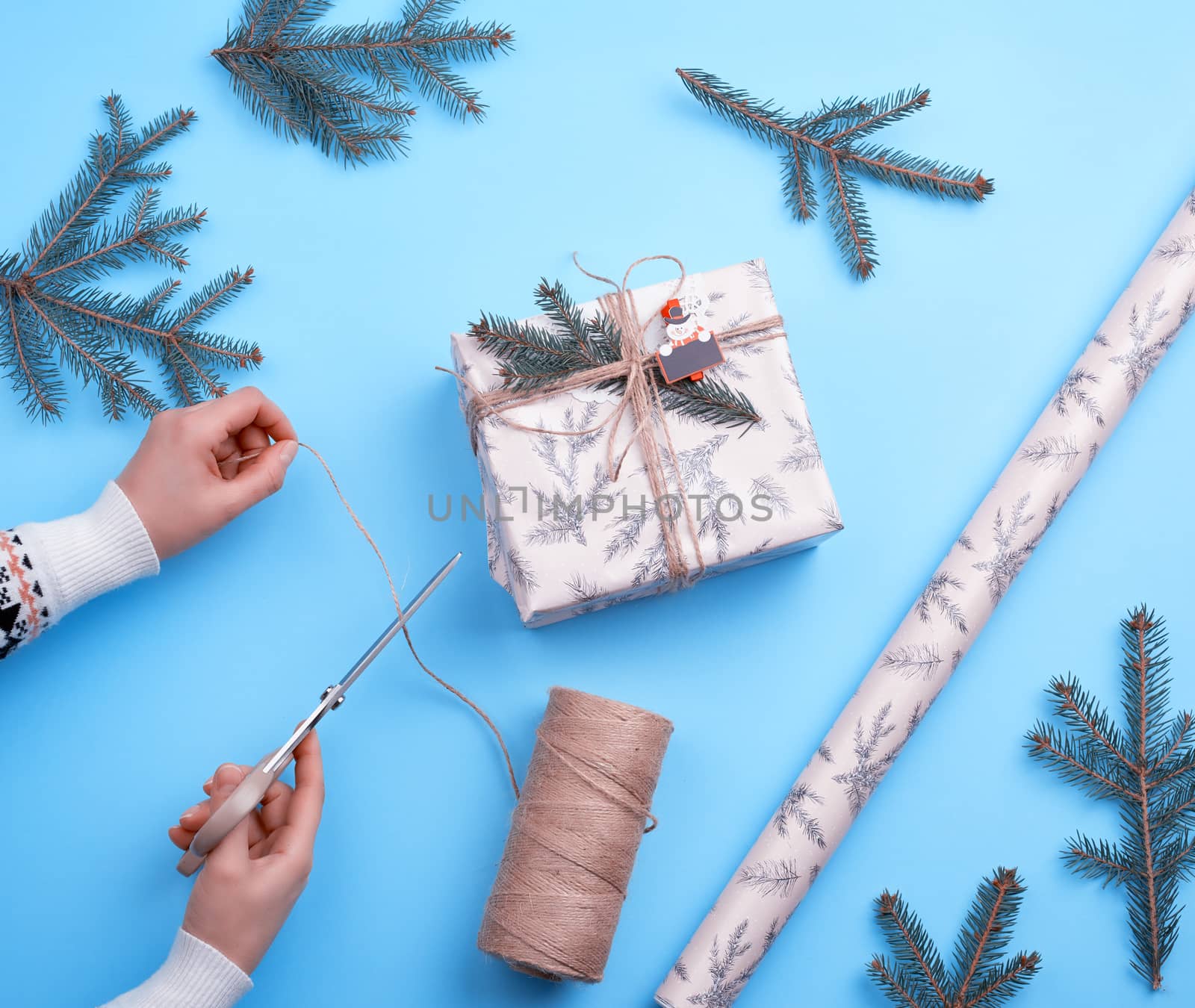 gift wrapped in pink paper and tied with a brown rope, female hand with scissors cuts a brown rope, congratulation concept