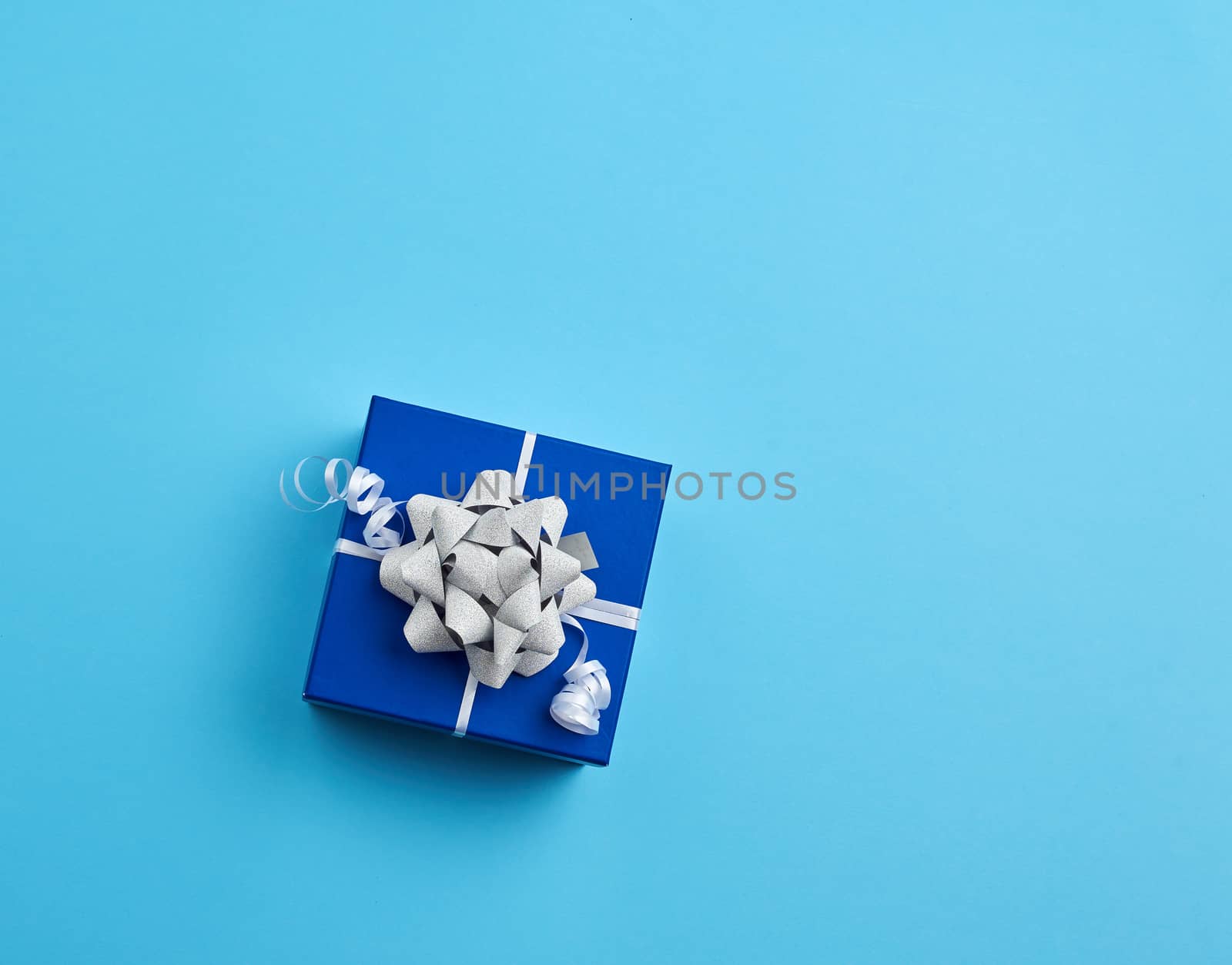 cardboard gift square box, bows, ribbons on a blue background, top view. Festive concept