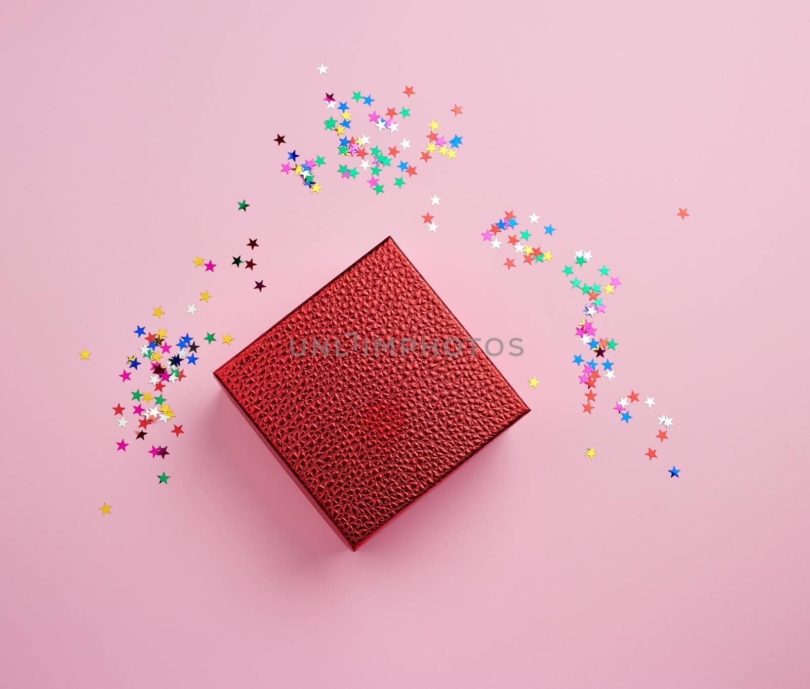 square red shiny box and multicolored sparkles on a pink background. Holiday concept. Package design. Festive concept.