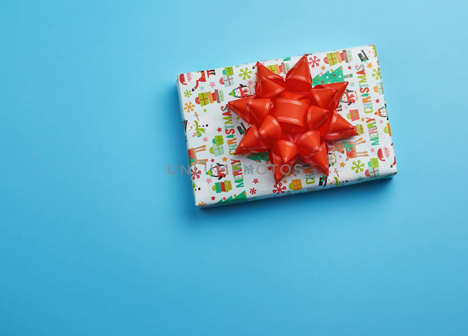 gift wrapped in multi-colored paper on a blue background, festive backdrop, top view, copy space