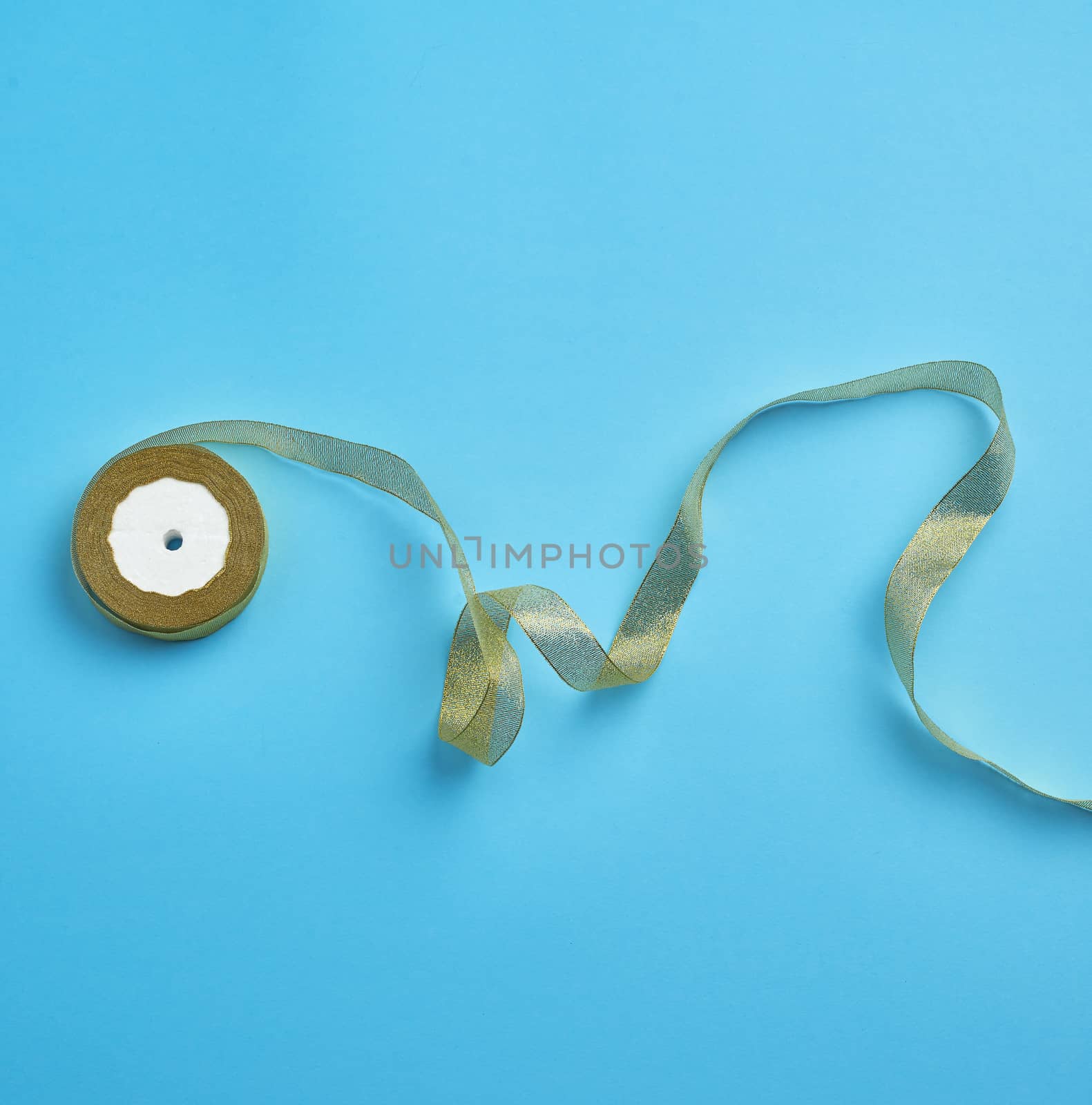 Shiny golden satin ribbon on a blue background. Beautiful banner for celebration design. Anniversary, birthday