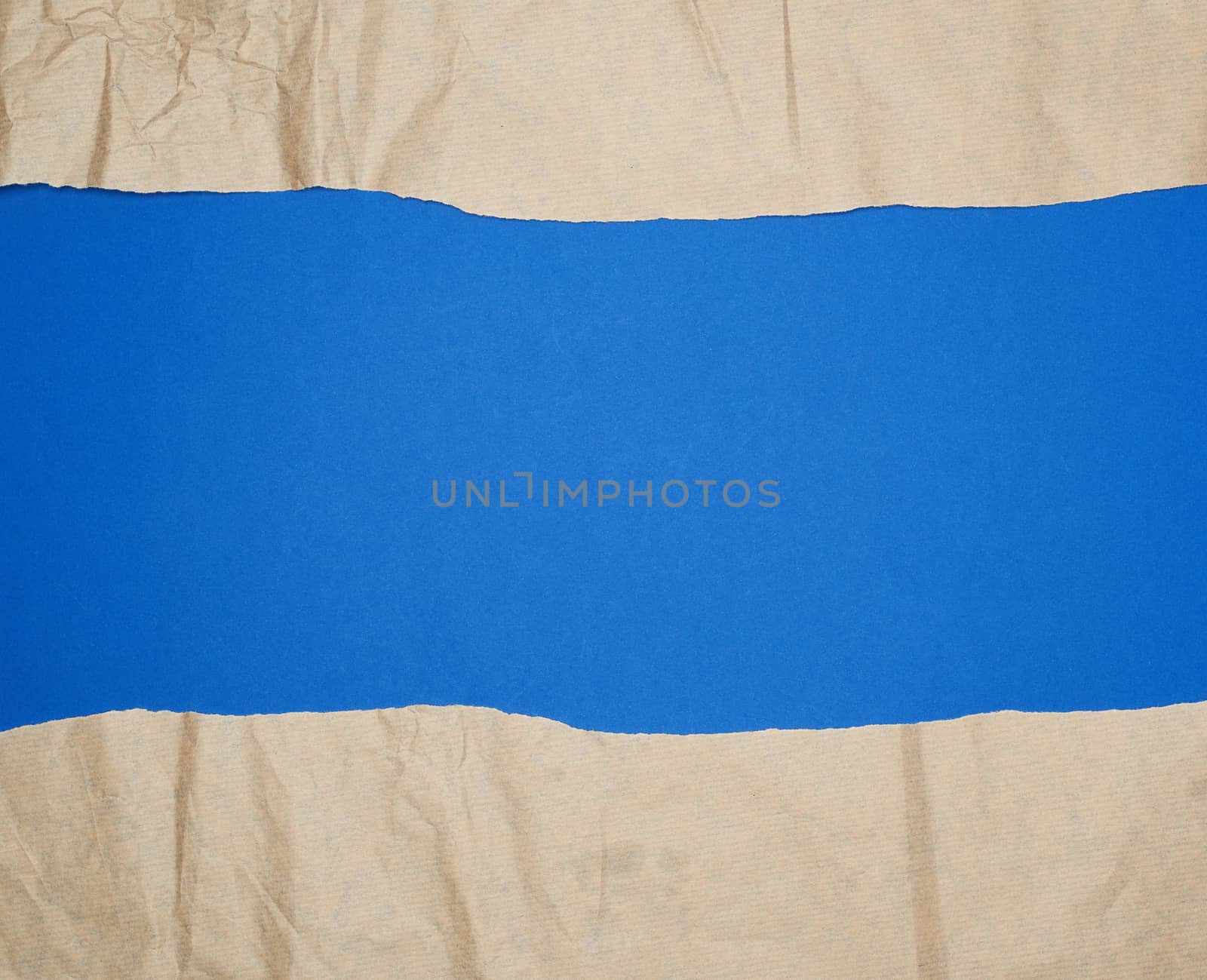 torn brown sheet of paper on a blue background, full frame, close up
