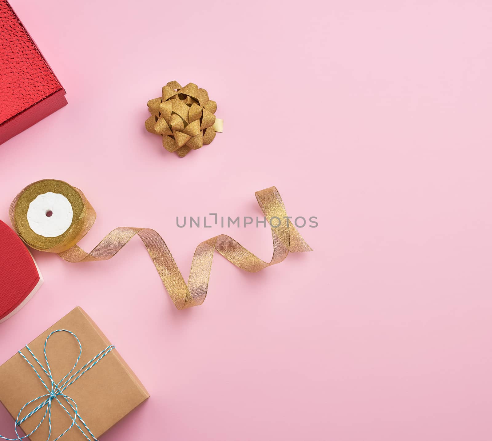 square gift boxes decorated with ribbons and bows on a pink background, top view, place for text