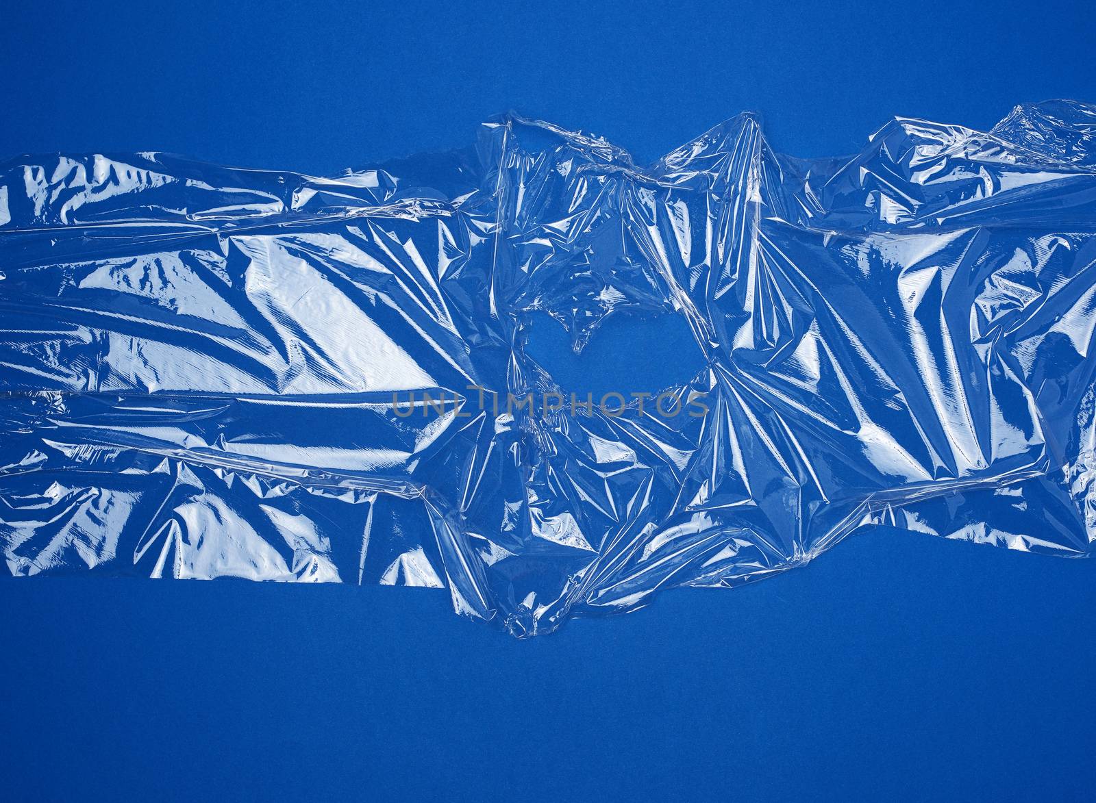 texture of a transparent stretching plastic film for packaging products on a blue background, full frame, close up