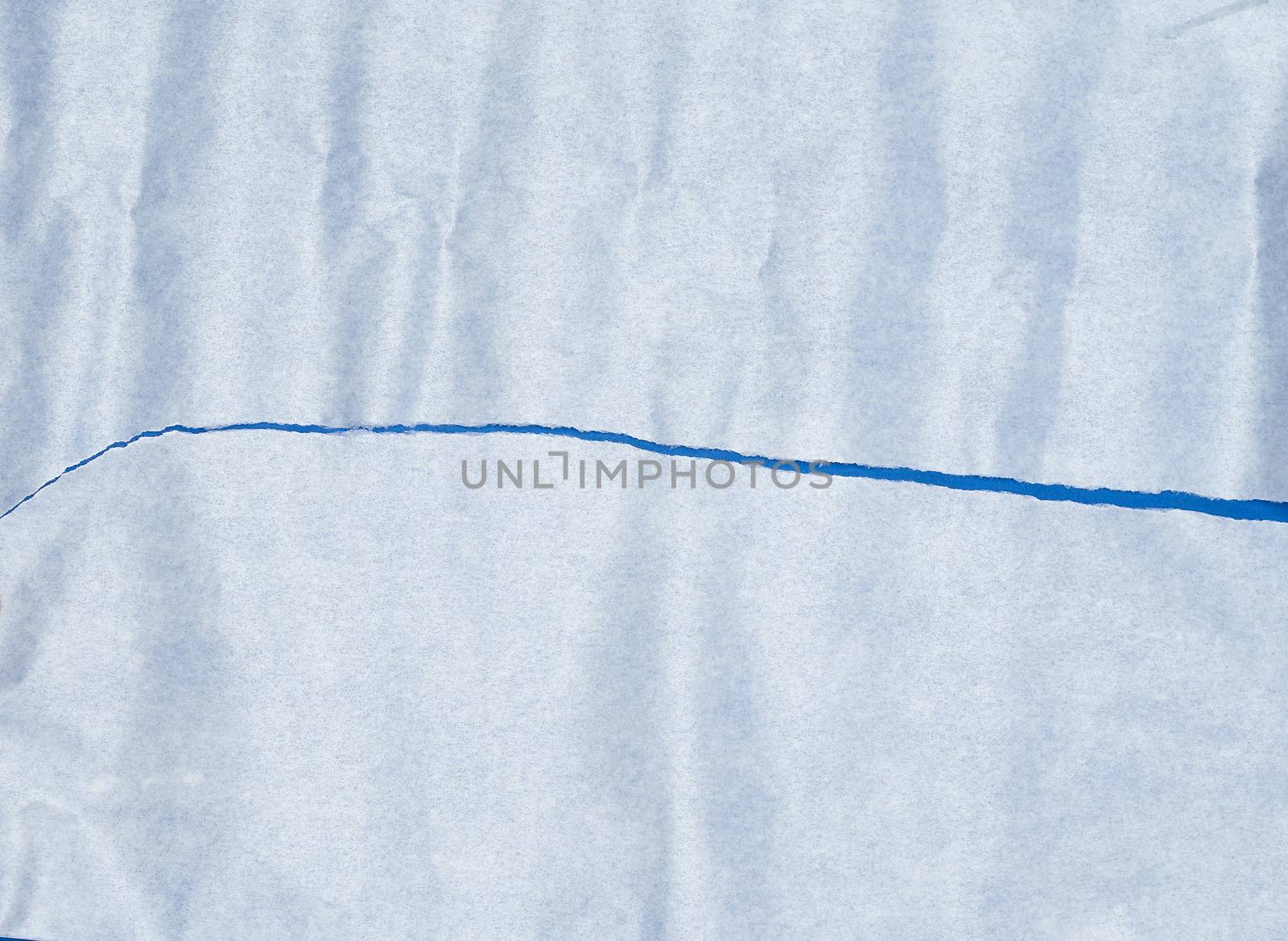 torn piece of white parchment paper on a blue background, close up