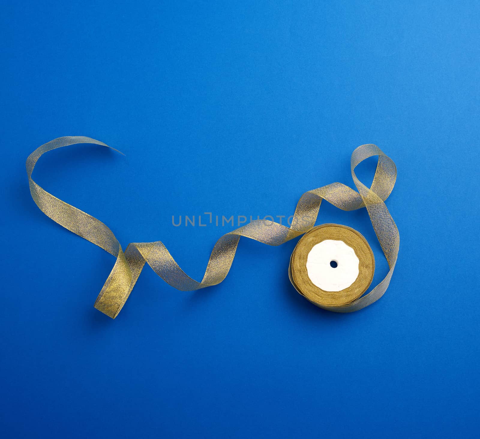 Shiny golden satin ribbon on a blue background. Beautiful banner for celebration design. Anniversary, birthday