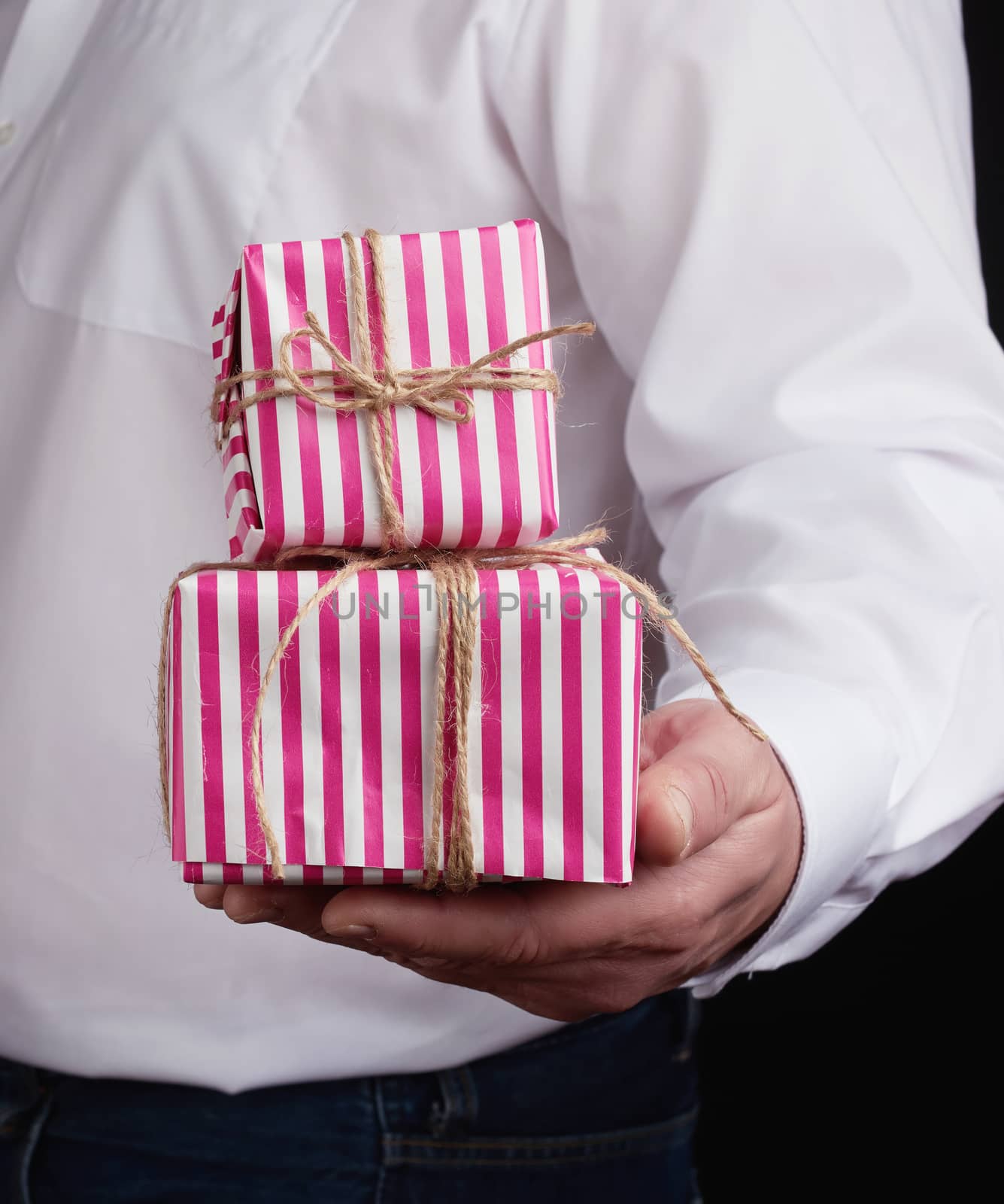adult man in a white shirt holds a pink gift cardboard box, concept of a congratulation on the holiday, anniversary, surprise