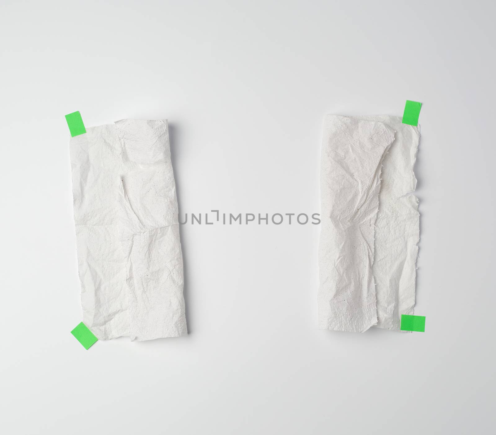 crumpled dirty white piece of paper towel glued with green paper velcro on a white background, place for text