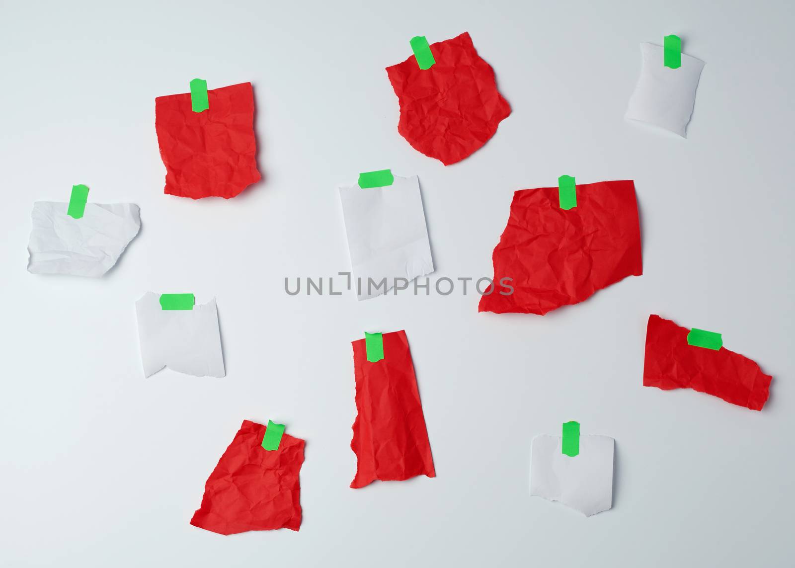 lot of torn red and white pieces of paper glued with green scotch tape on a white background, place for text