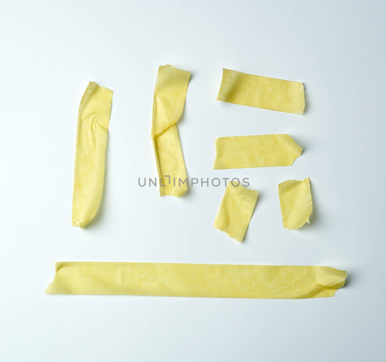 set of various pieces of yellow sticky paper tape on a white background, close up