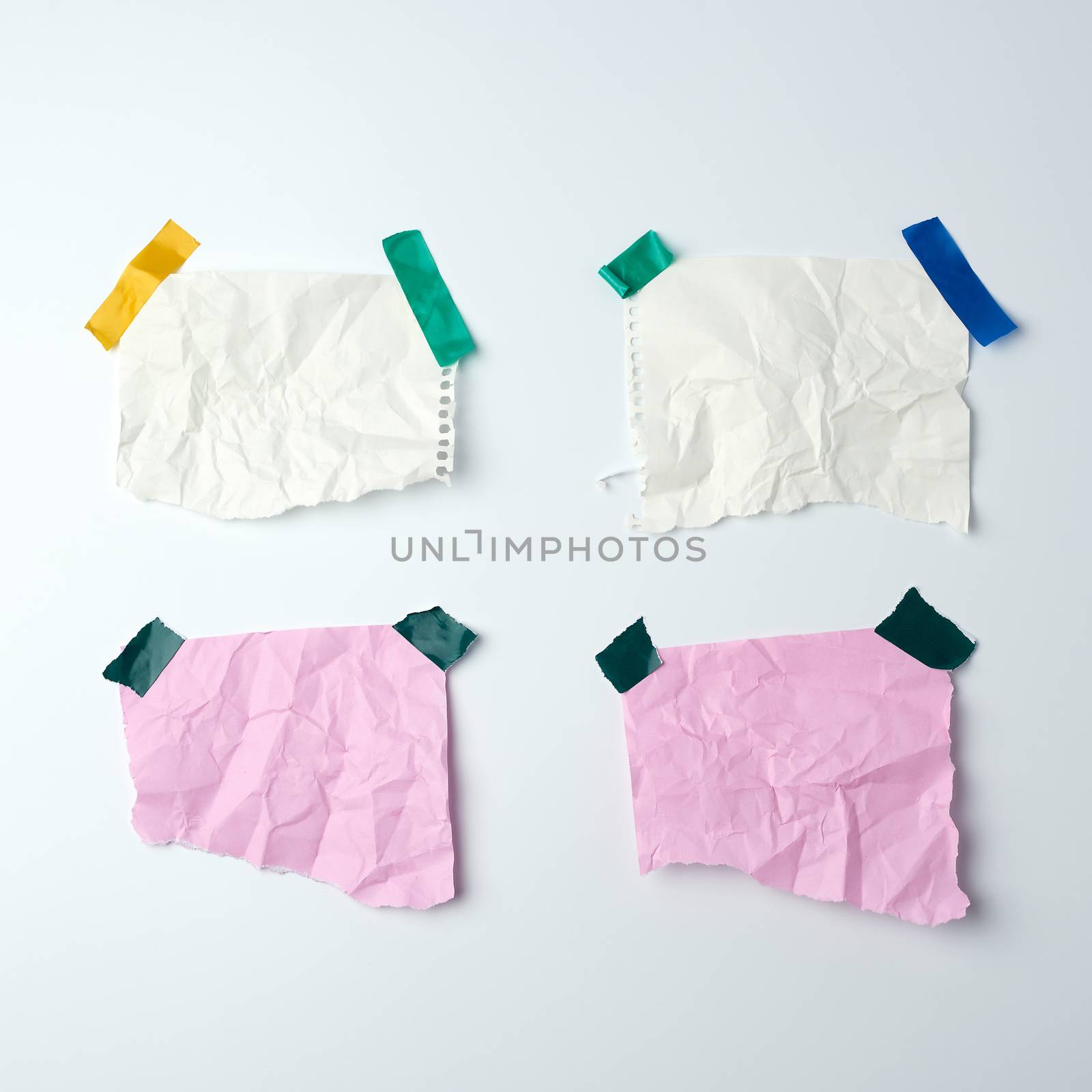 blank crumpled sheets of paper glued with rubber colored adhesive tape on a white background, copy space