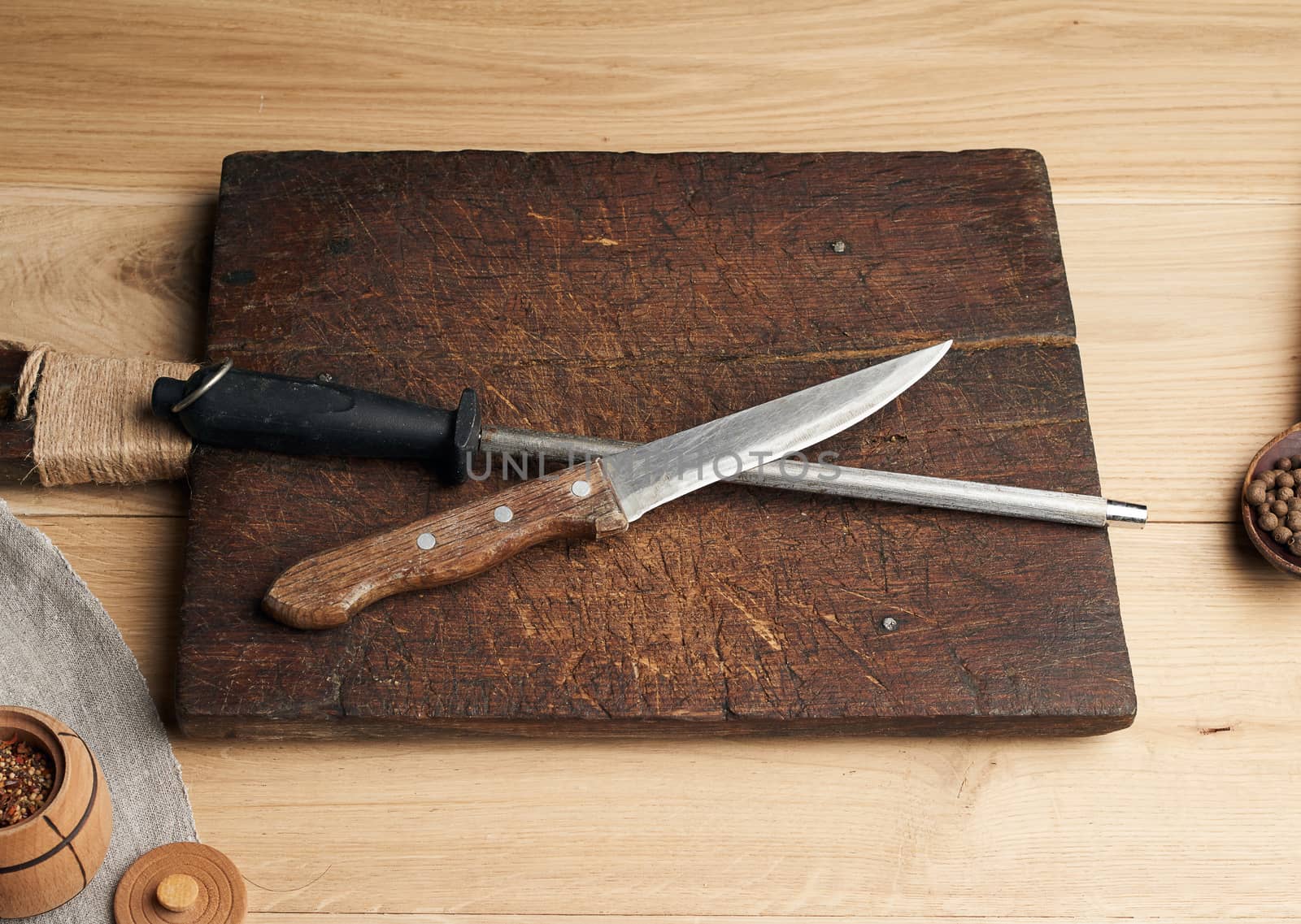 old sharp knife and sharpener with a handle on a wooden background, top view