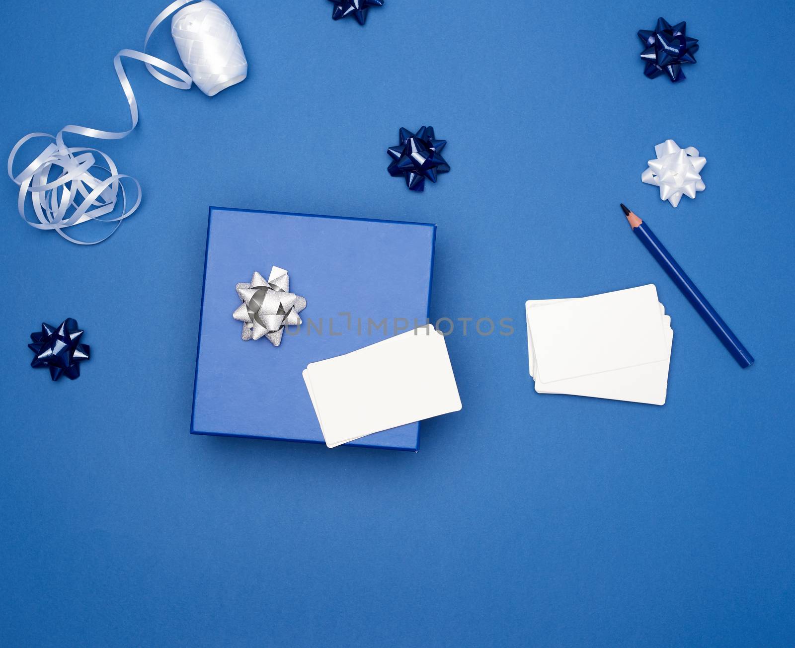 closed cardboard gift square boxes, bows, ribbons for packaging on a dark blue background, top view, trend colors