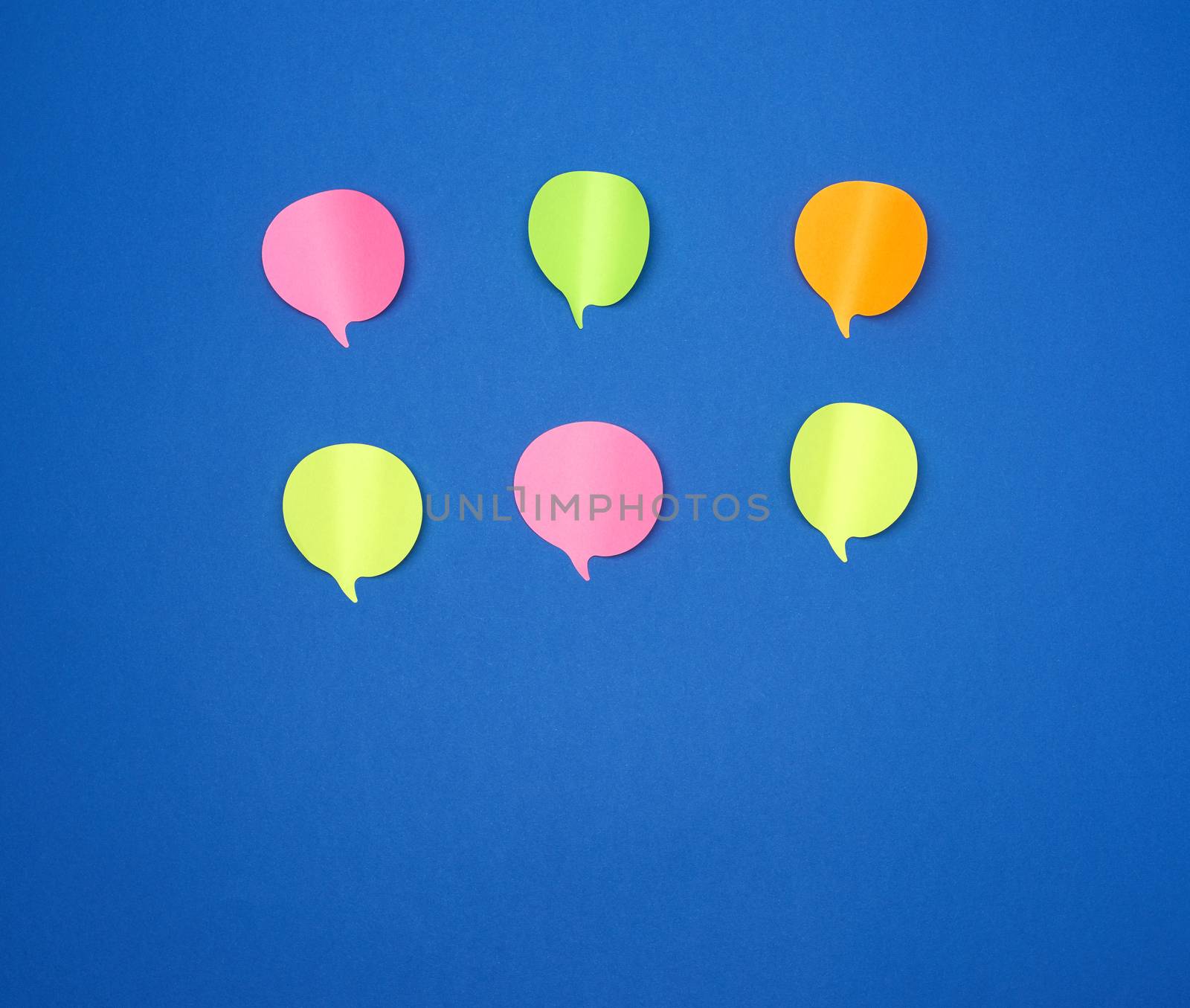 multicolored empty paper stickers in the form of clouds on a blue background, copy space