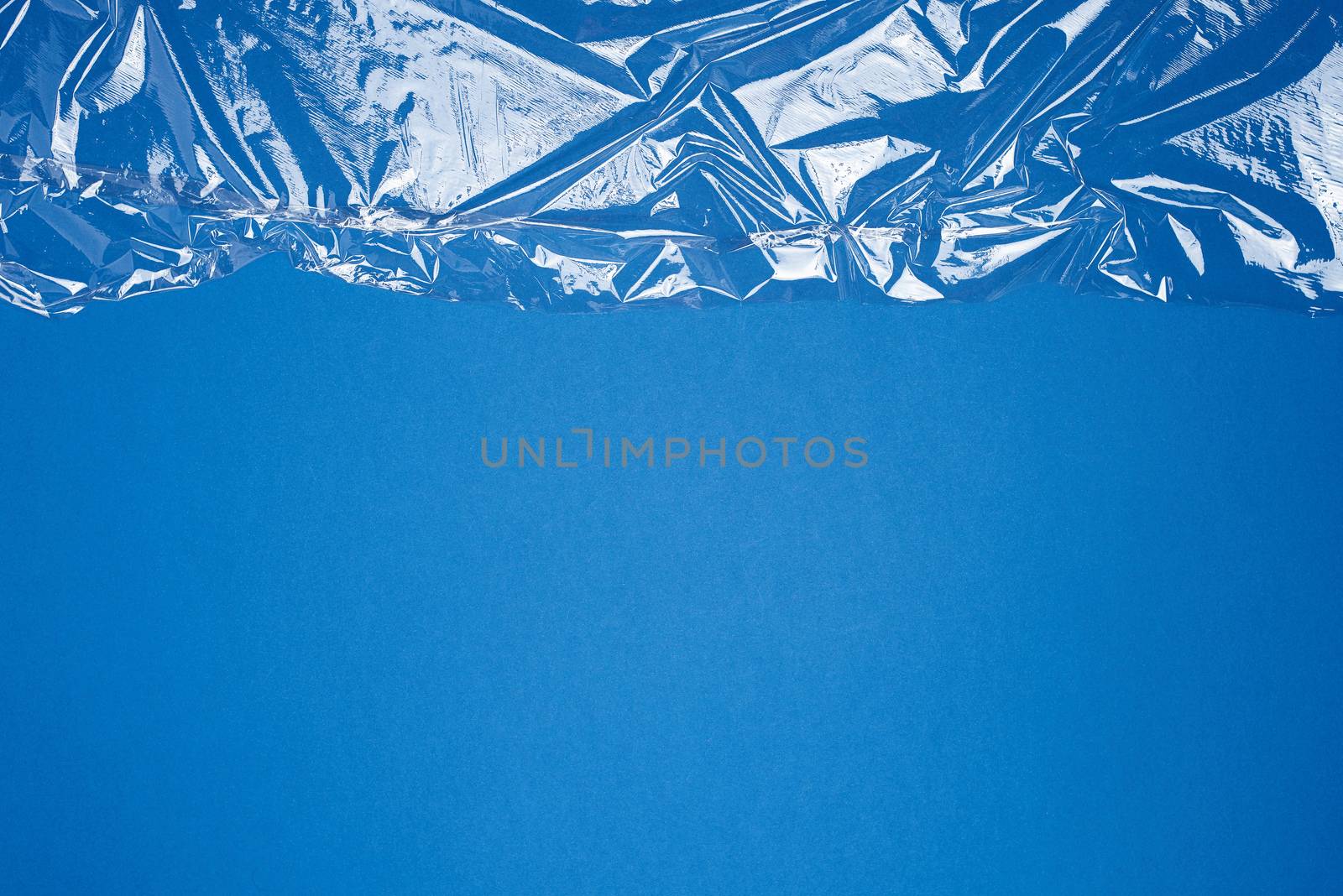 texture of a transparent stretching plastic film for packaging products on a blue background, full frame, close up