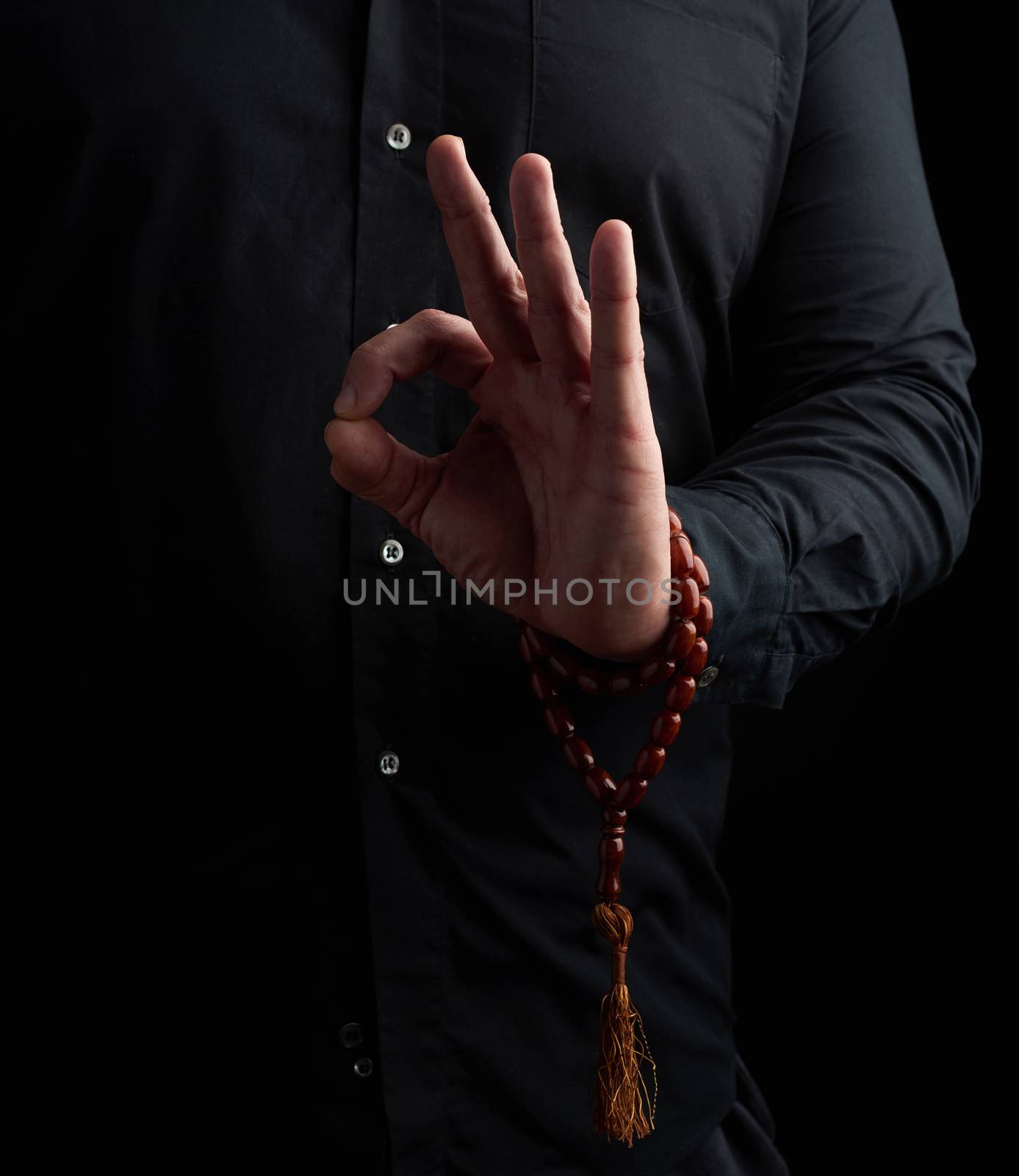 man in a black shirt shows with his left hand the gian mudra, concept of meditation and relaxation