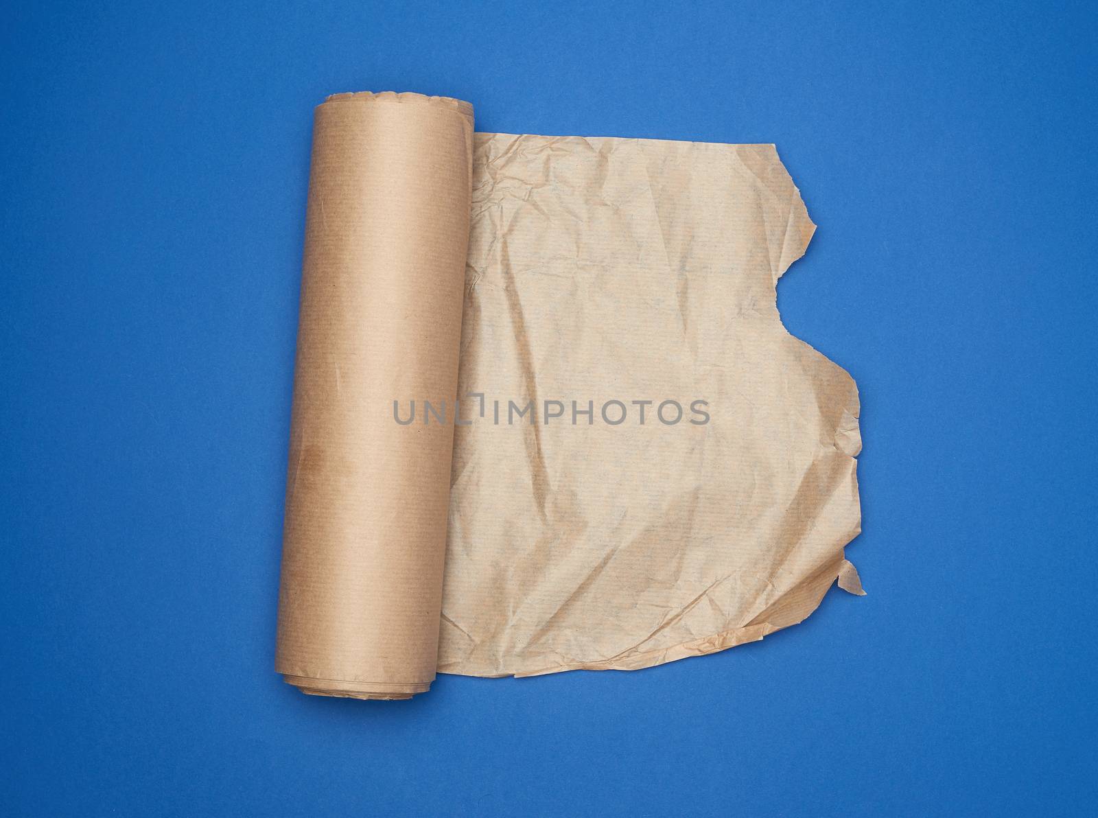 roll of brown parchment paper on a blue background, copy space, top view