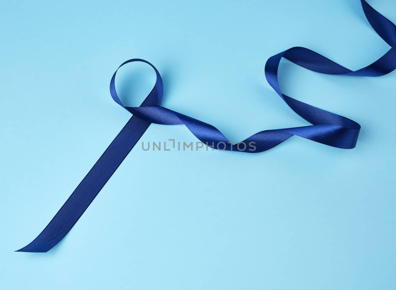 blue silk thin ribbon twisted on a blue background, trendy classic color, close up