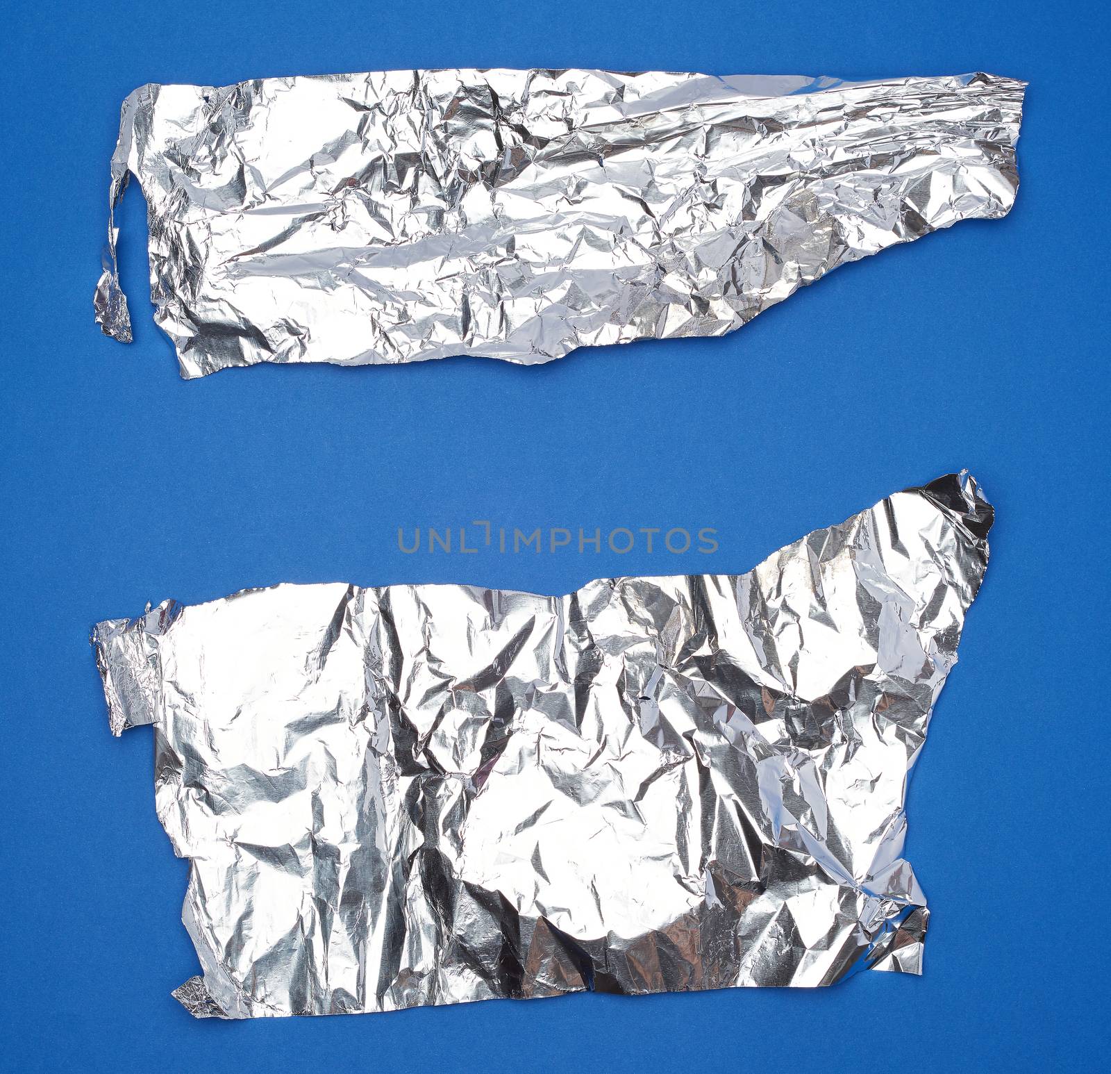 crumpled silver foil sheet, full frame, blue background 