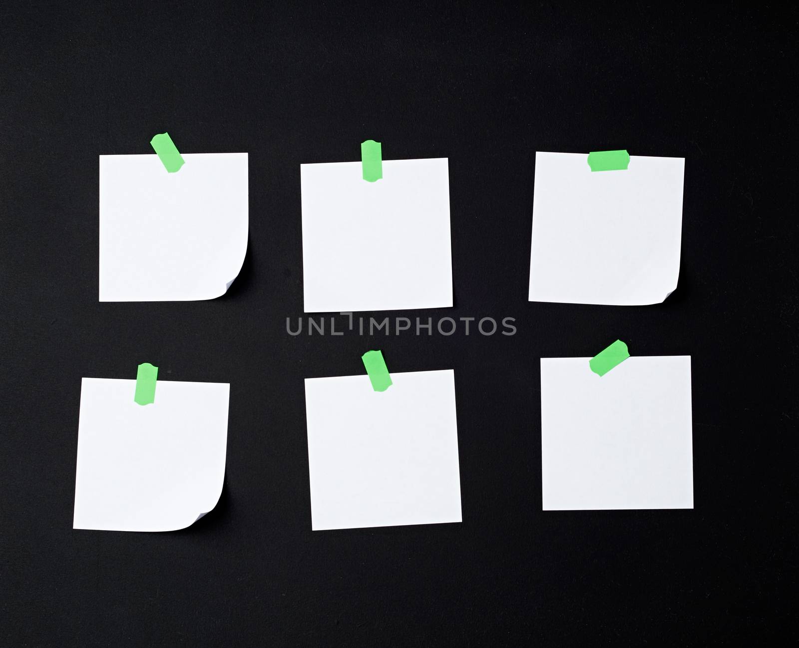 set of square white blank sheets of paper glued with green sticky paper on black background