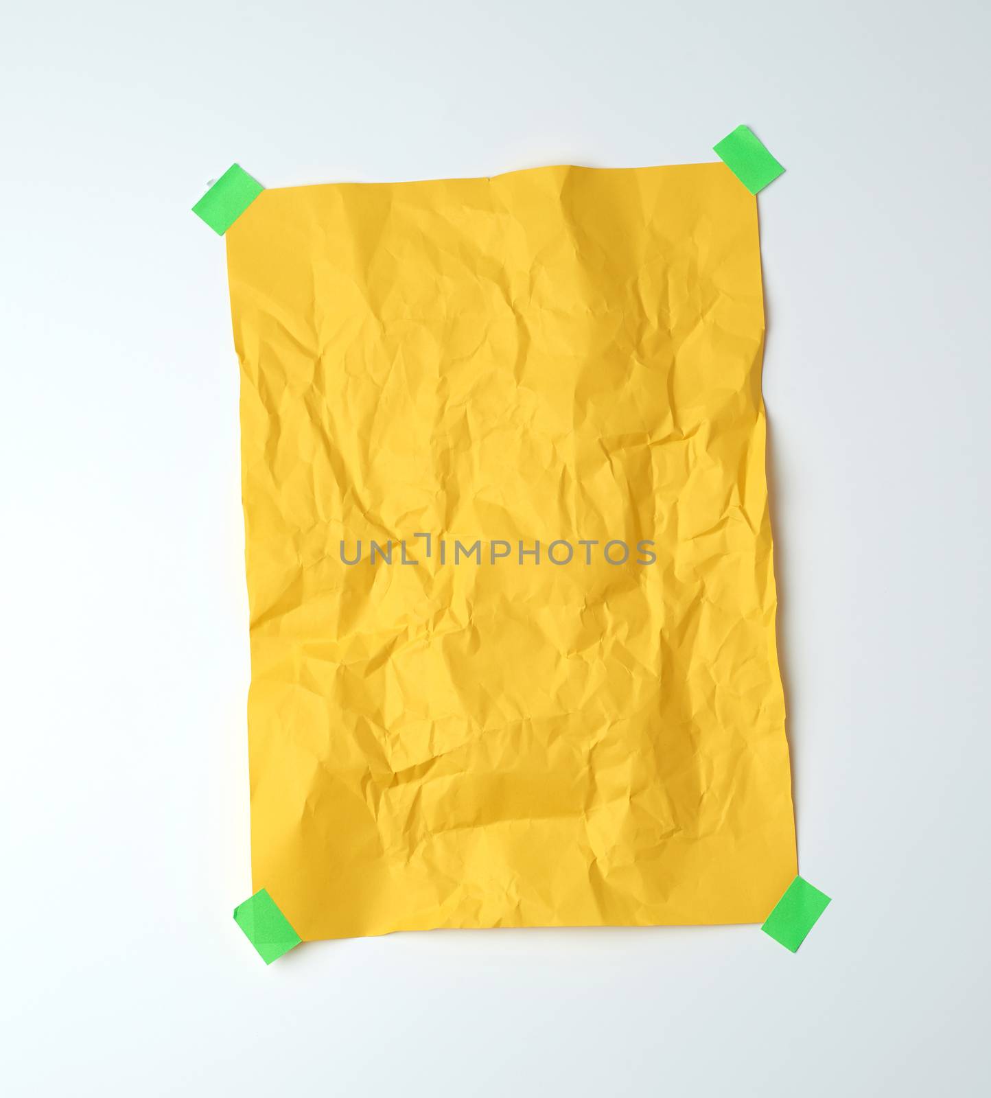 empty yellow crumpled sheet of paper glued with green sticky pieces of paper on a white background, place for text