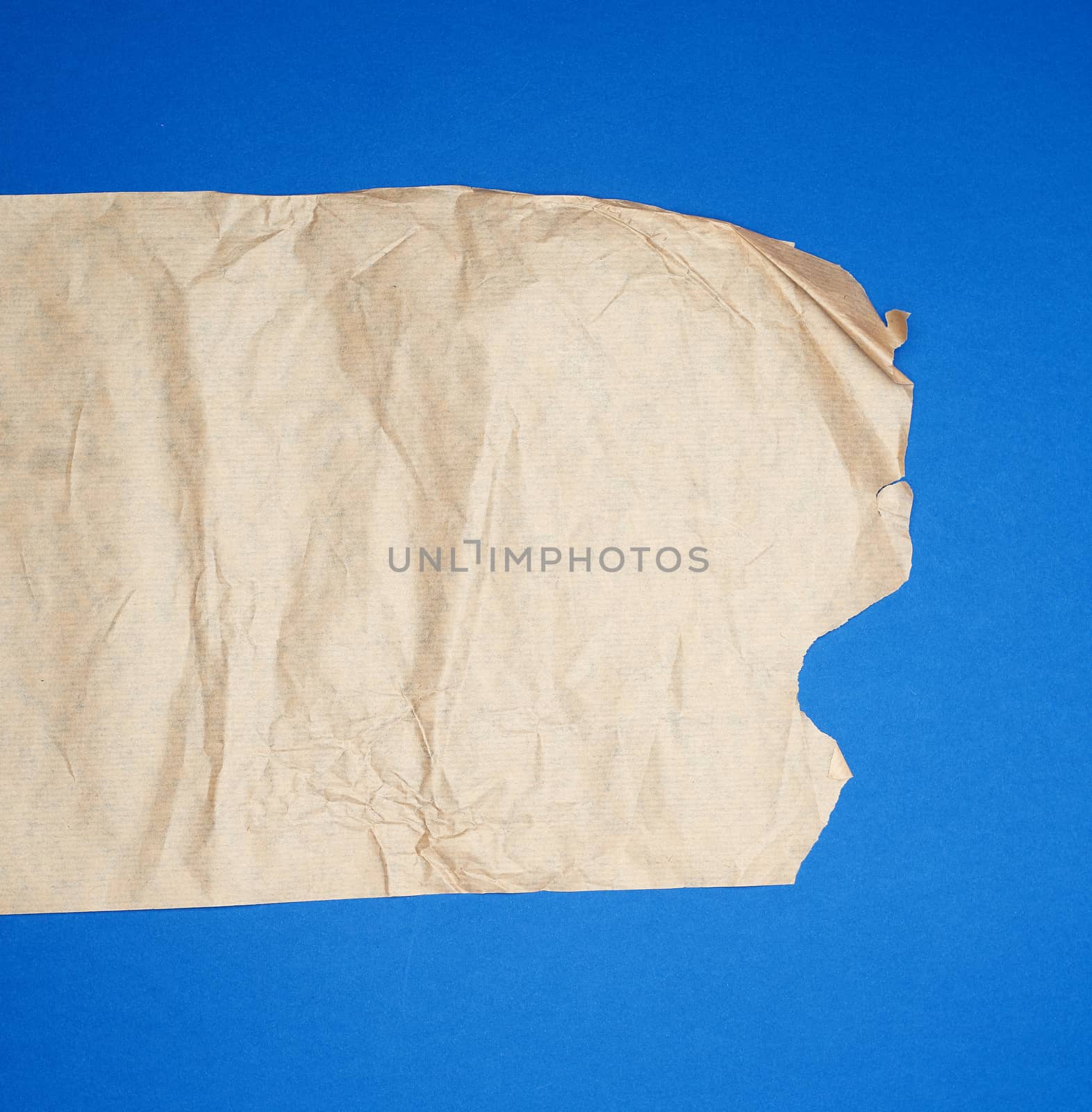 torn brown sheet of paper on a blue background, full frame, close up