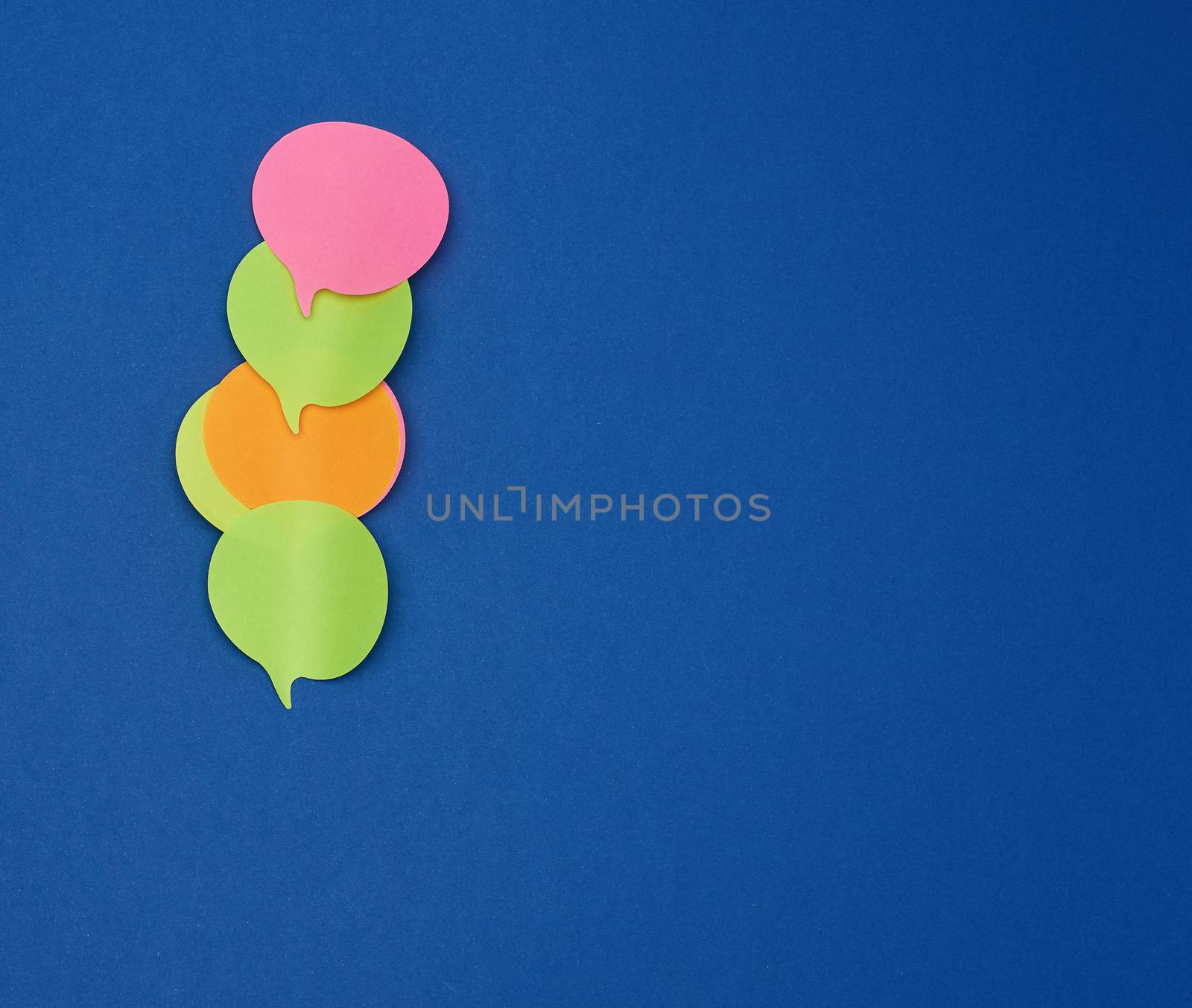 multicolored empty paper stickers in the form of clouds on a blue background, copy space
