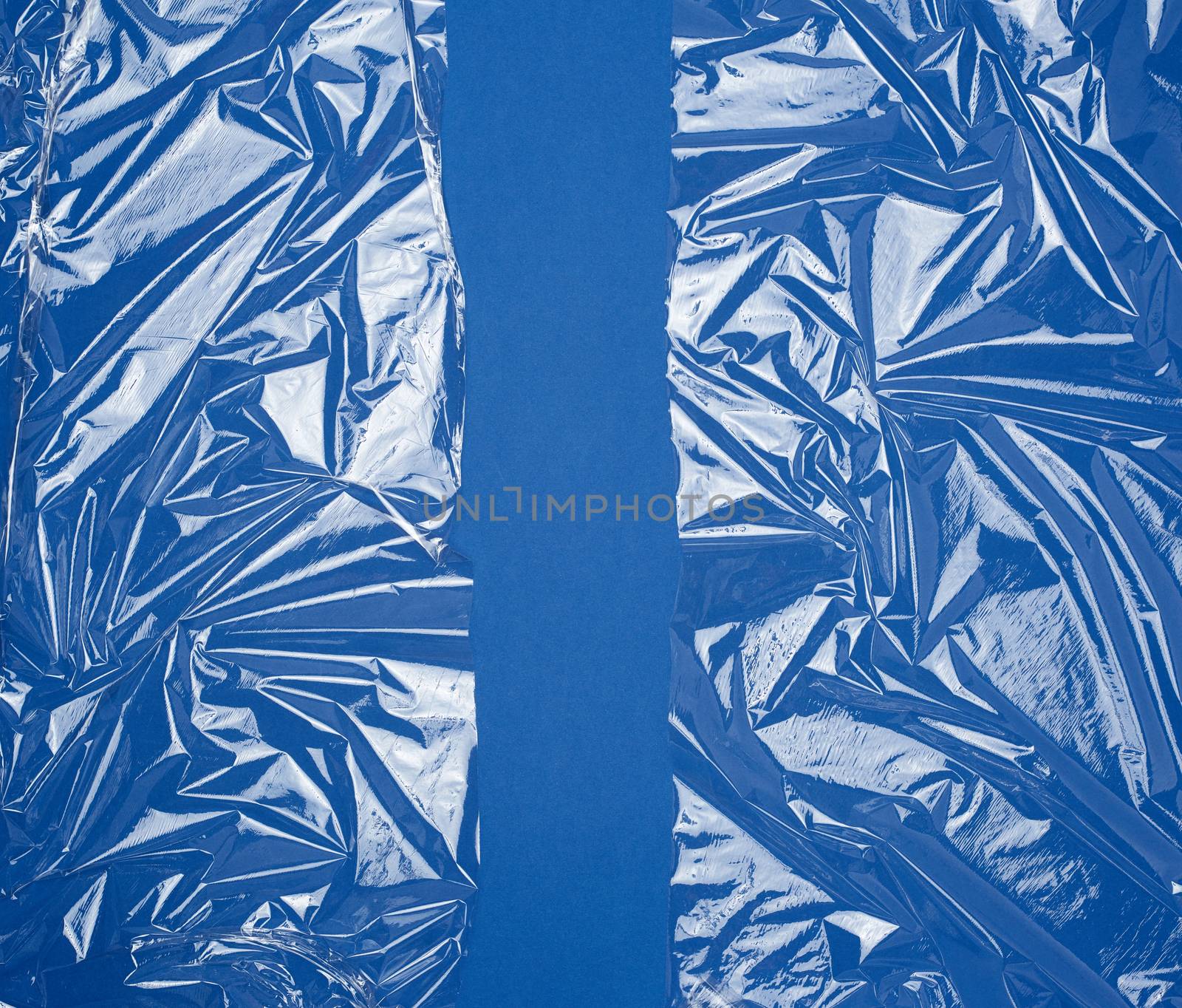 texture of a transparent stretching plastic film for packaging products on a blue background, full frame, close up