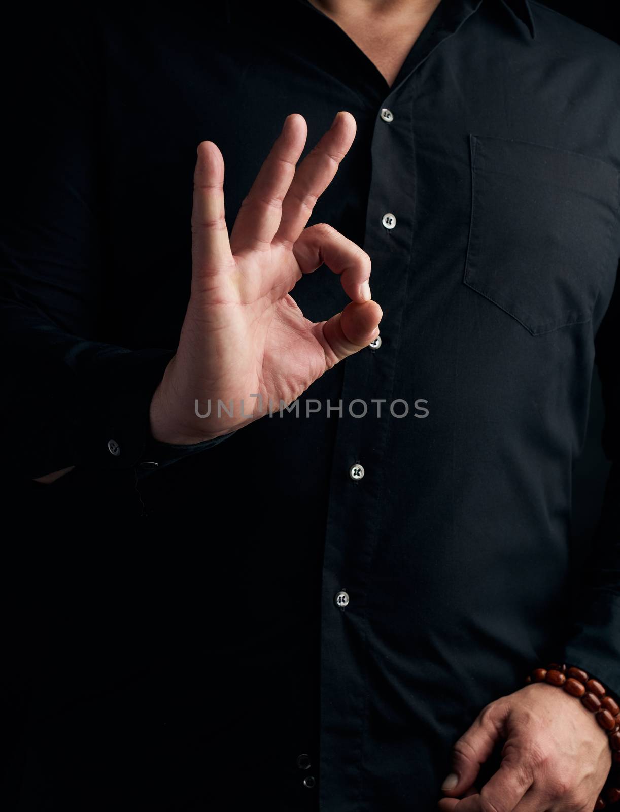 man in a black shirt shows with his hand the gian mudra, concept of meditation and relaxation