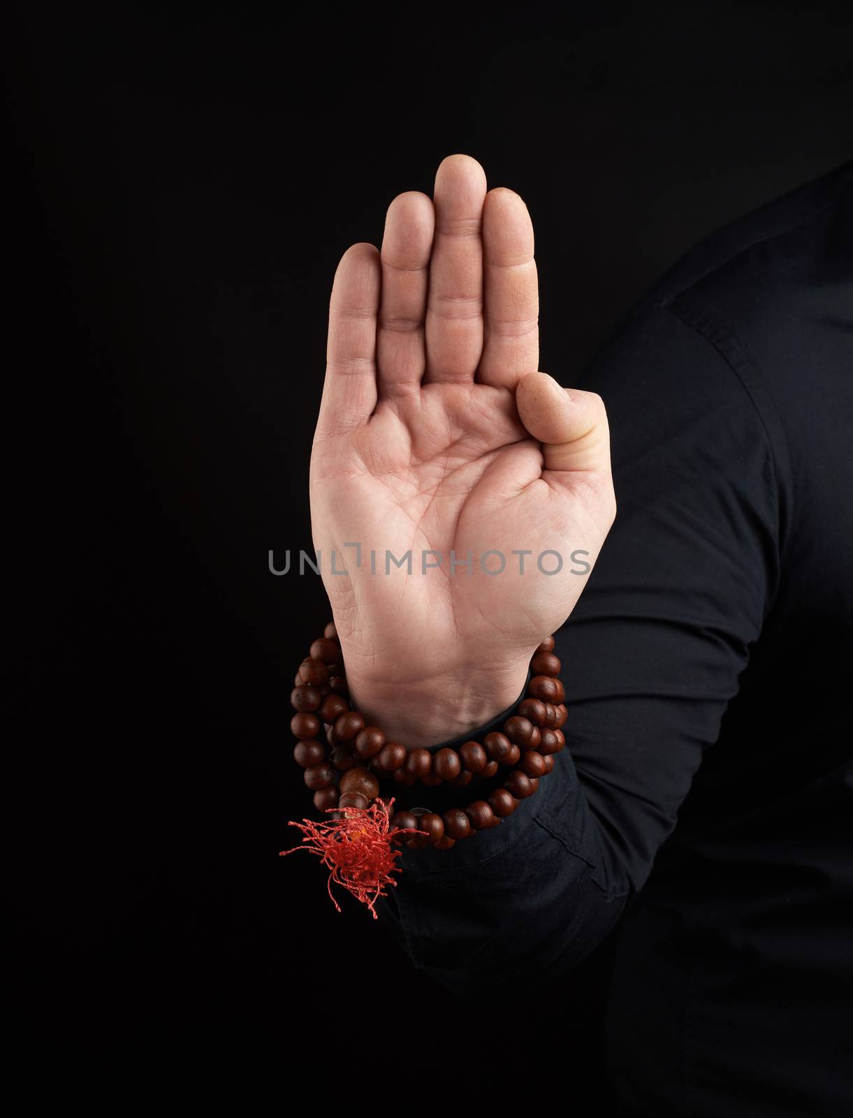 hand of an adult male shows abhayaprada mudra on a dark background, protective gesture. Symbolizes strength and fearlessness.