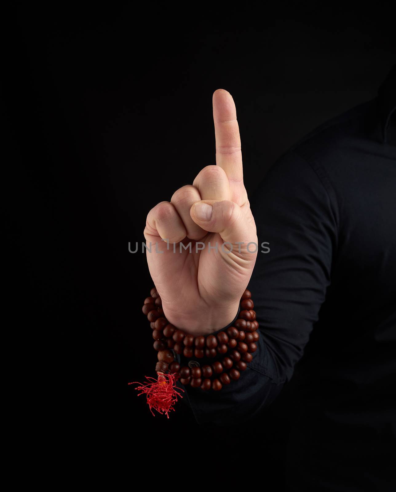 hand of an adult male shows a dragon tooth mudra on a dark background