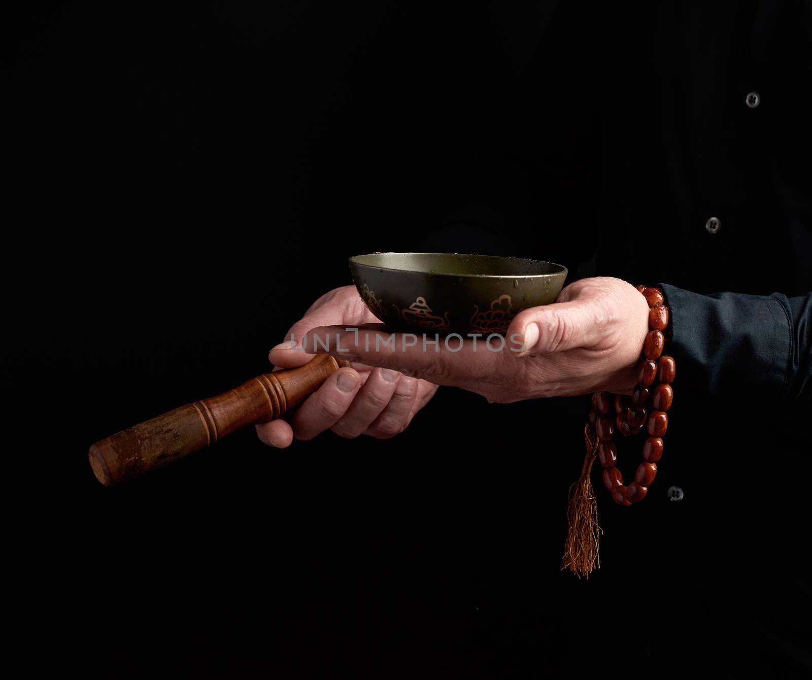 man in a black shirt rotates a wooden stick around a copper Tibetan bowl. ritual of meditation, prayers and immersion in a trance. Alternative treatment
