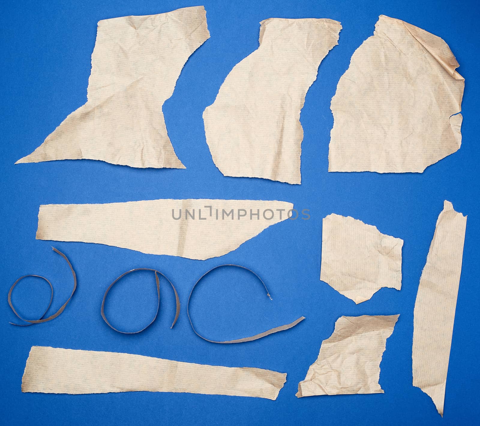 set of various pieces of torn brown crumpled paper on a blue background, close up