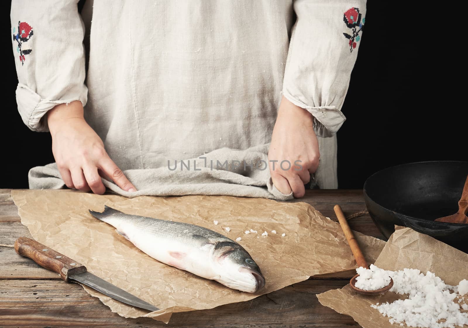fresh whole sea bass fish lies on the table, cooking process, dark background
