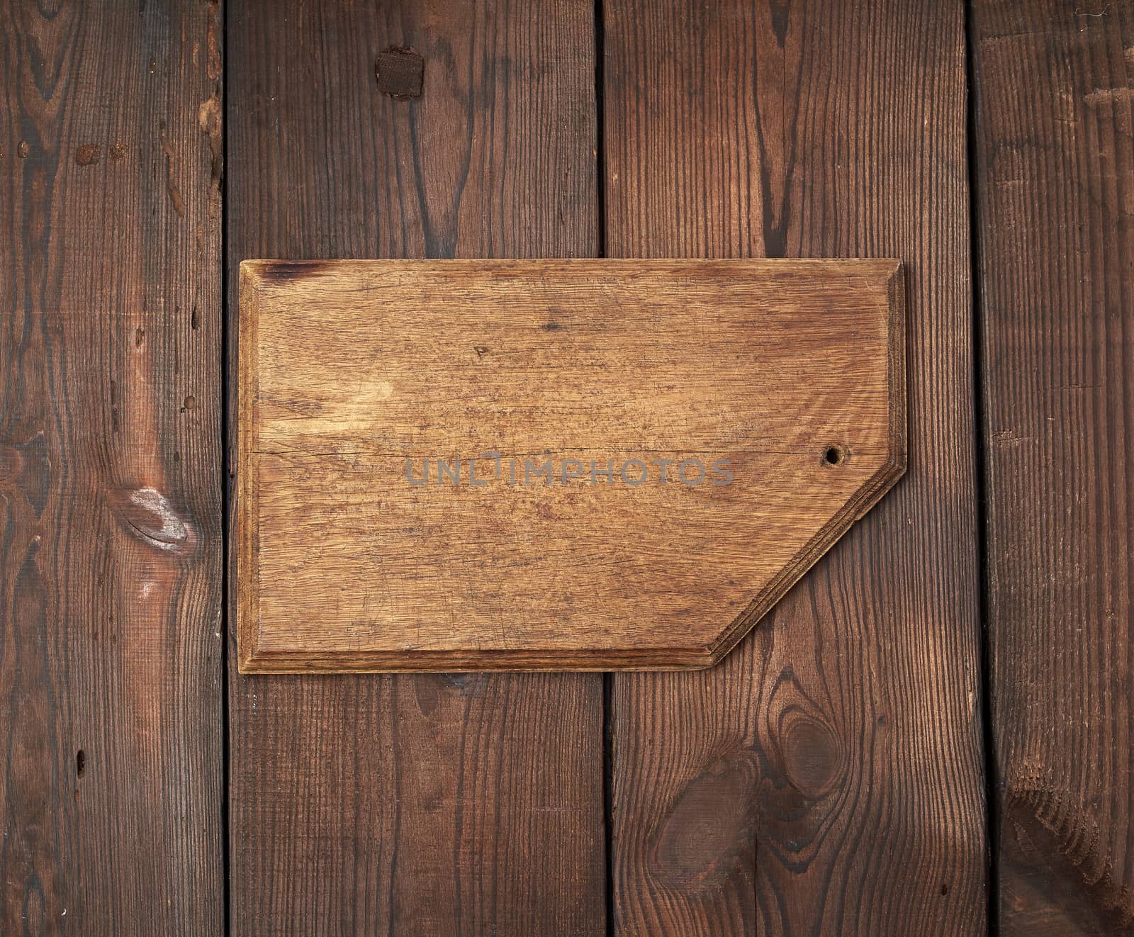 very old empty wooden rectangular cutting board, top view, brown wooden background 