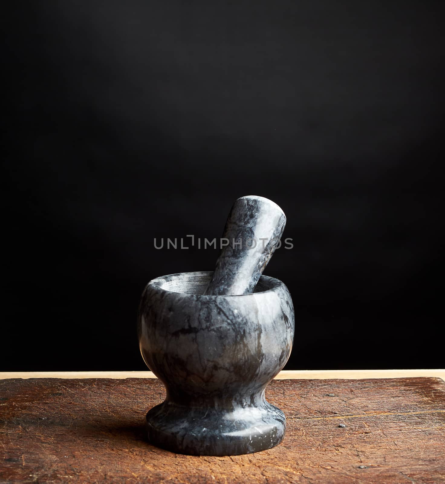 stone mortar with pestle for grinding spices on a brown wooden board, low key