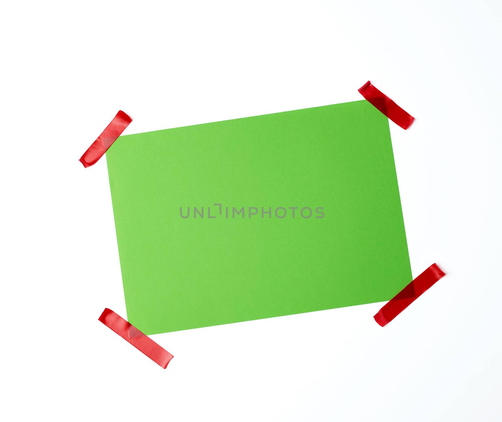 blank green sheet of paper stuck with red sticky tape on a white background, place for text