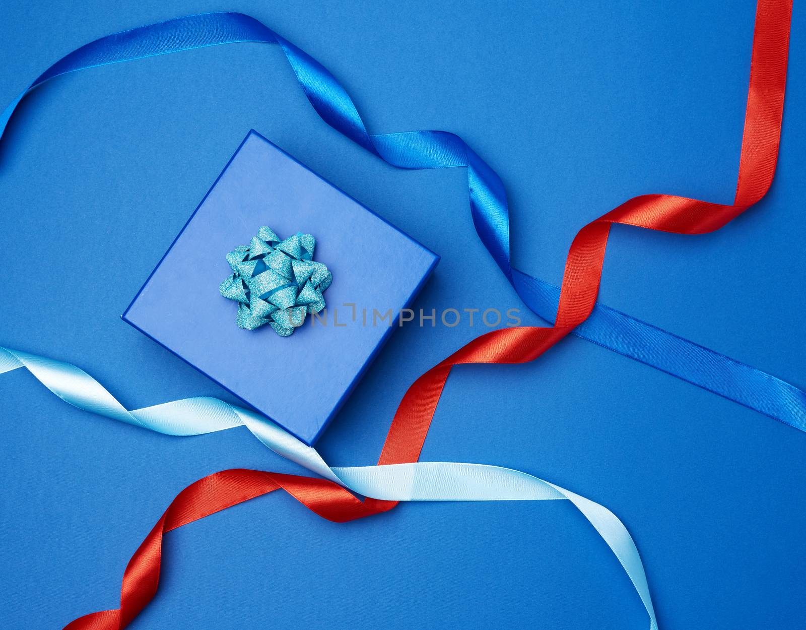 cardboard gift square box, bows, ribbons for packaging on a dark blue background, top view, trend colors