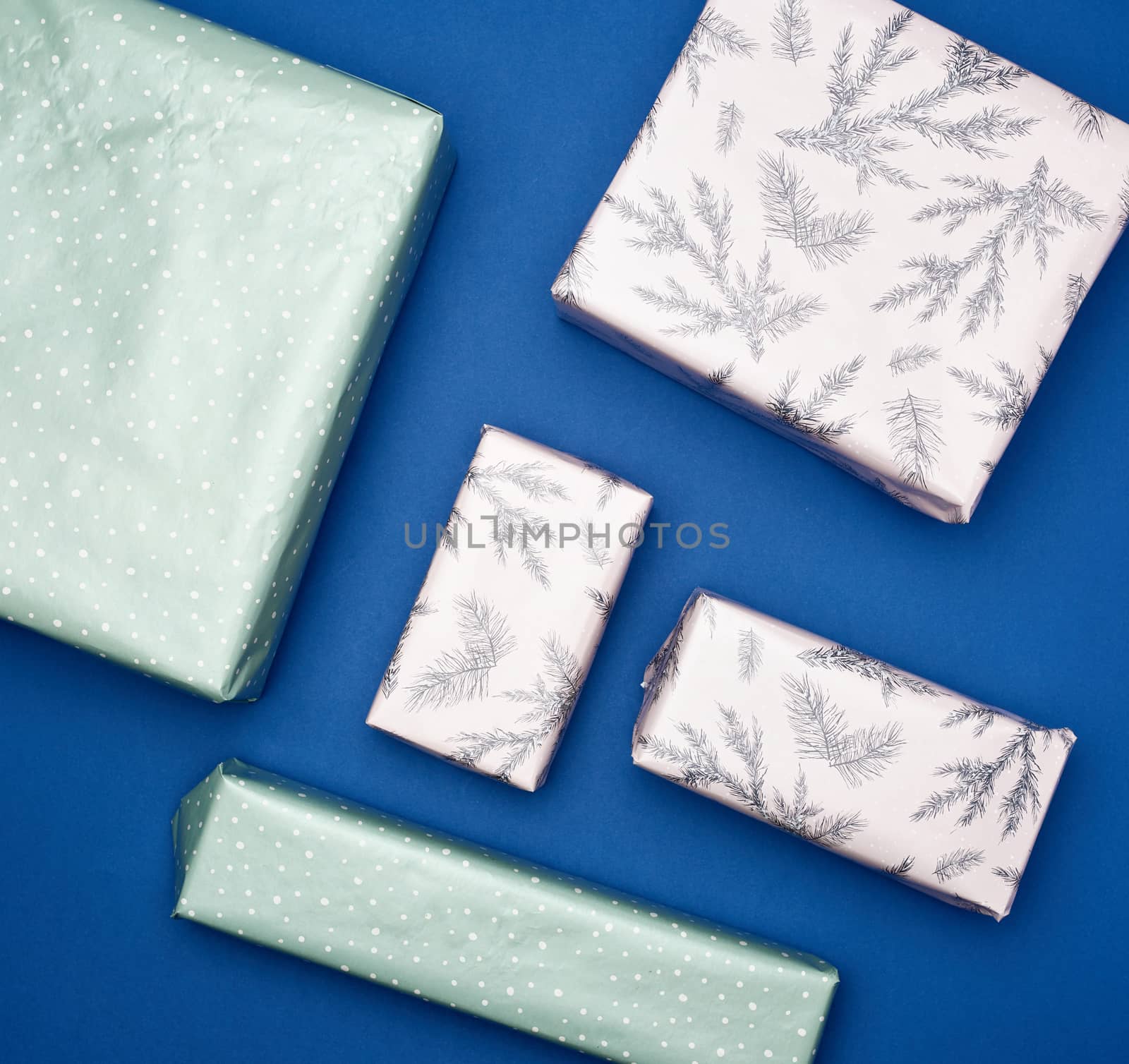 various boxes packed in paper on a blue background, holiday gifts, top view