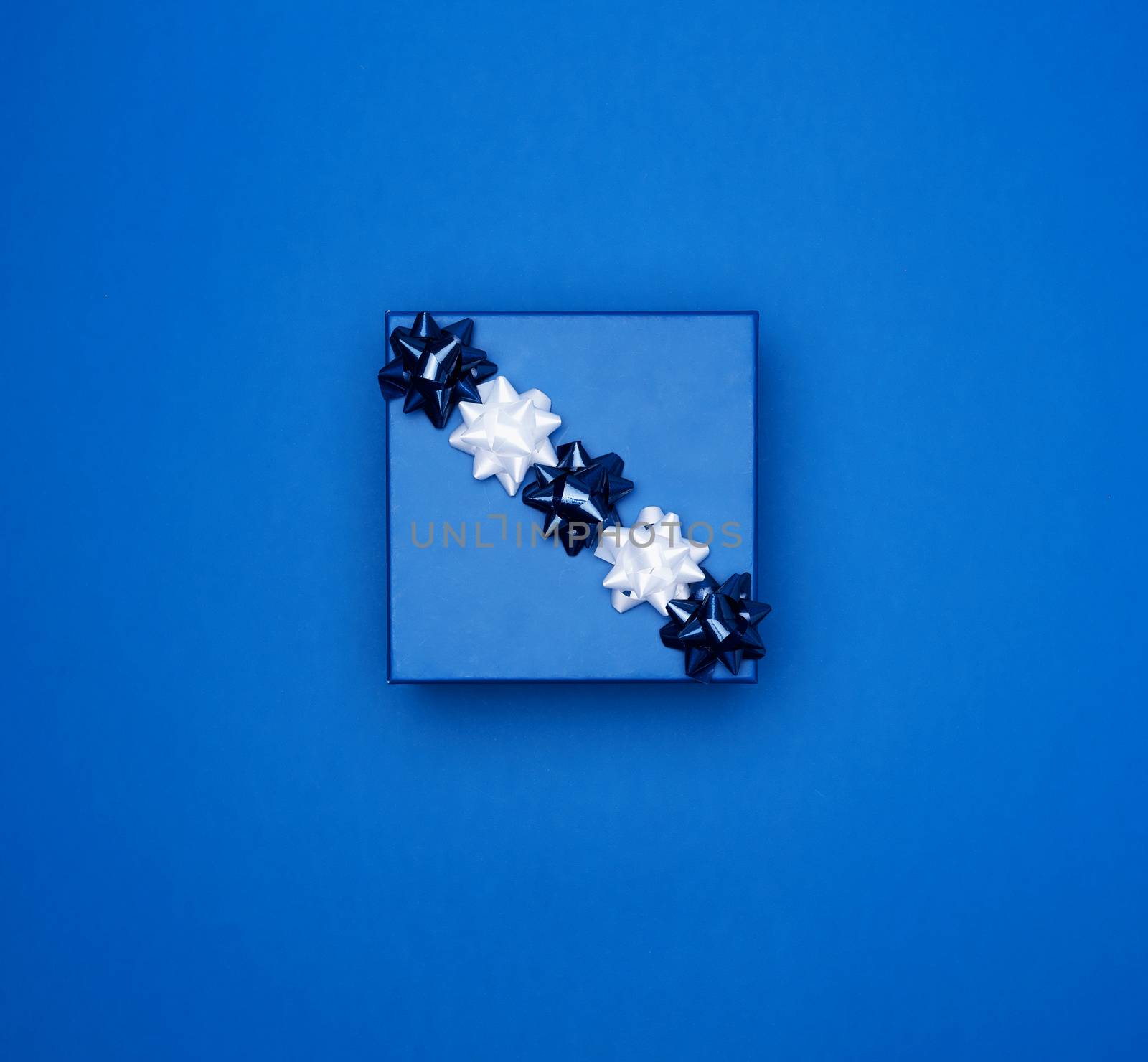 blue square box with a gift with a bow on a blue classic background, top view, empty place for an inscription