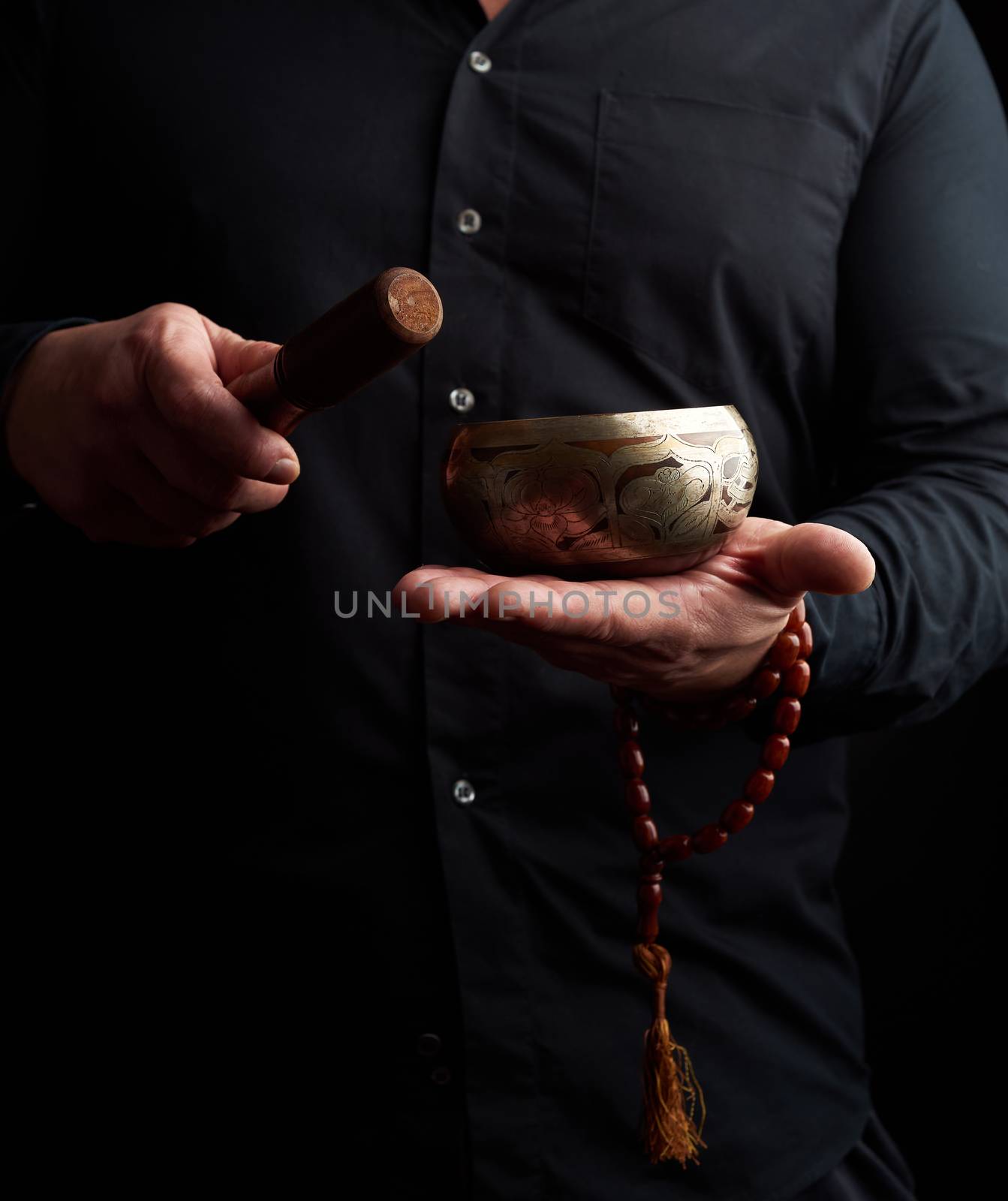 man in a black shirt holds a Tibetan brass singing bowl and a wo by ndanko