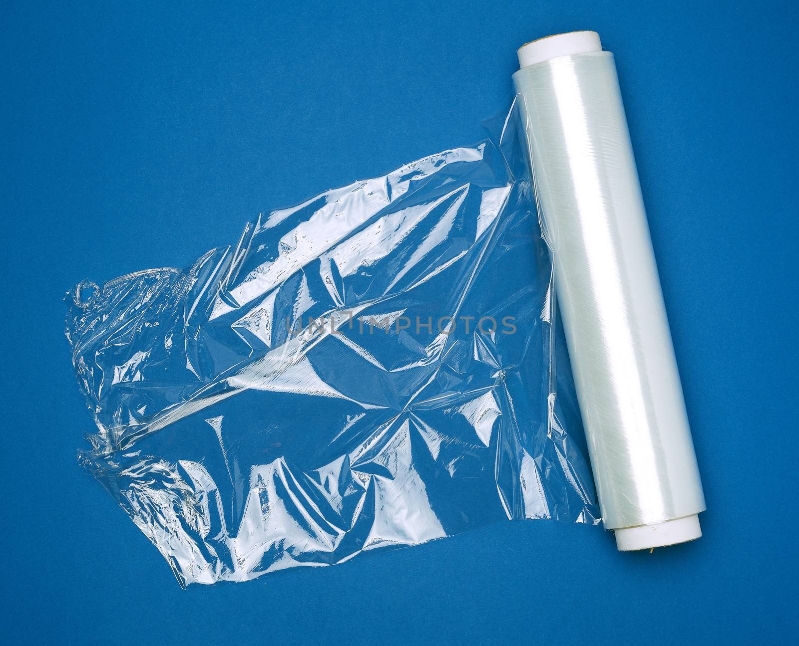 big roll of wound white transparent film for wrapping food, dark blue background, top view