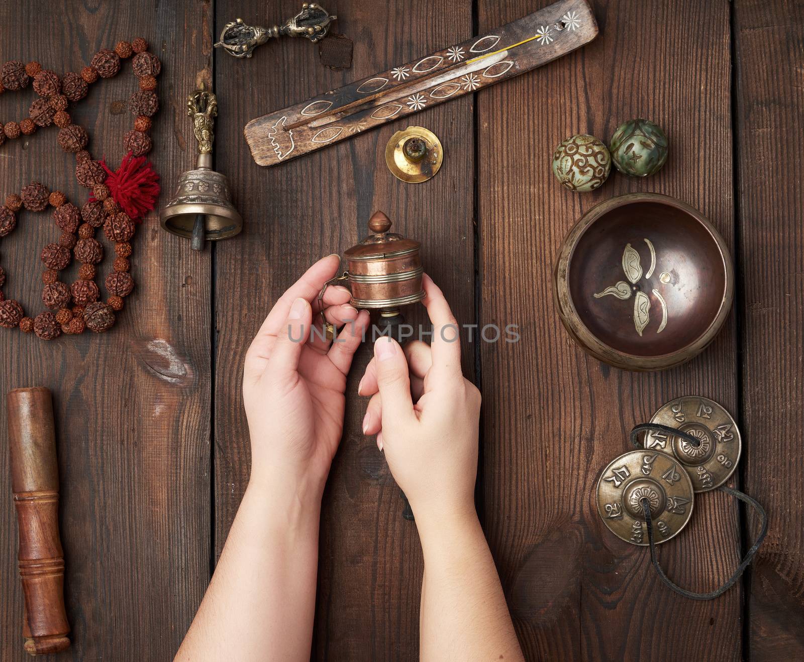 female hands hold a prayer drum on the wooden table, items for alternative medicine, sound massage and meditation