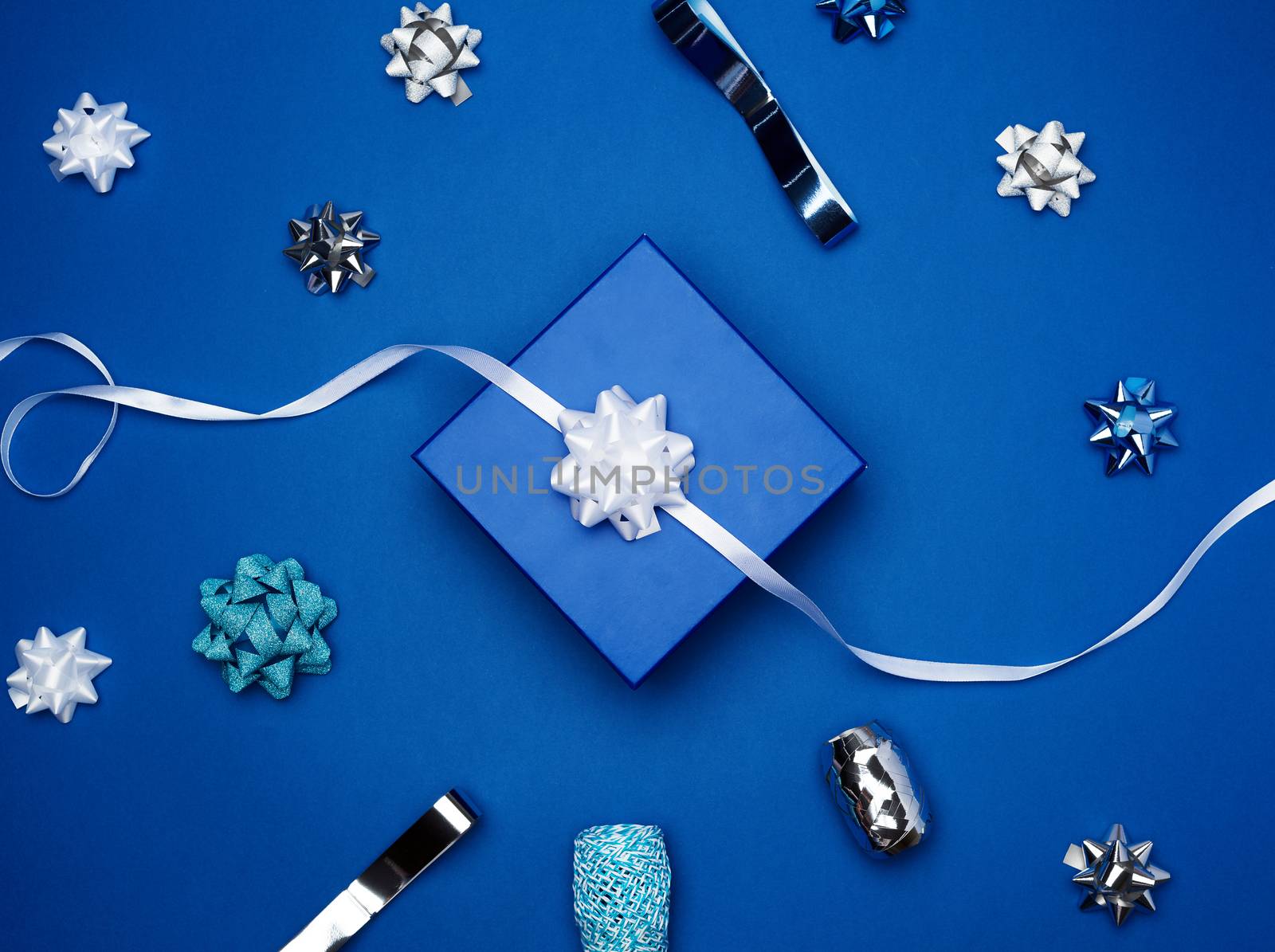 cardboard gift square boxes, bows, ribbons for packaging on a dark blue background, top view, trend colors