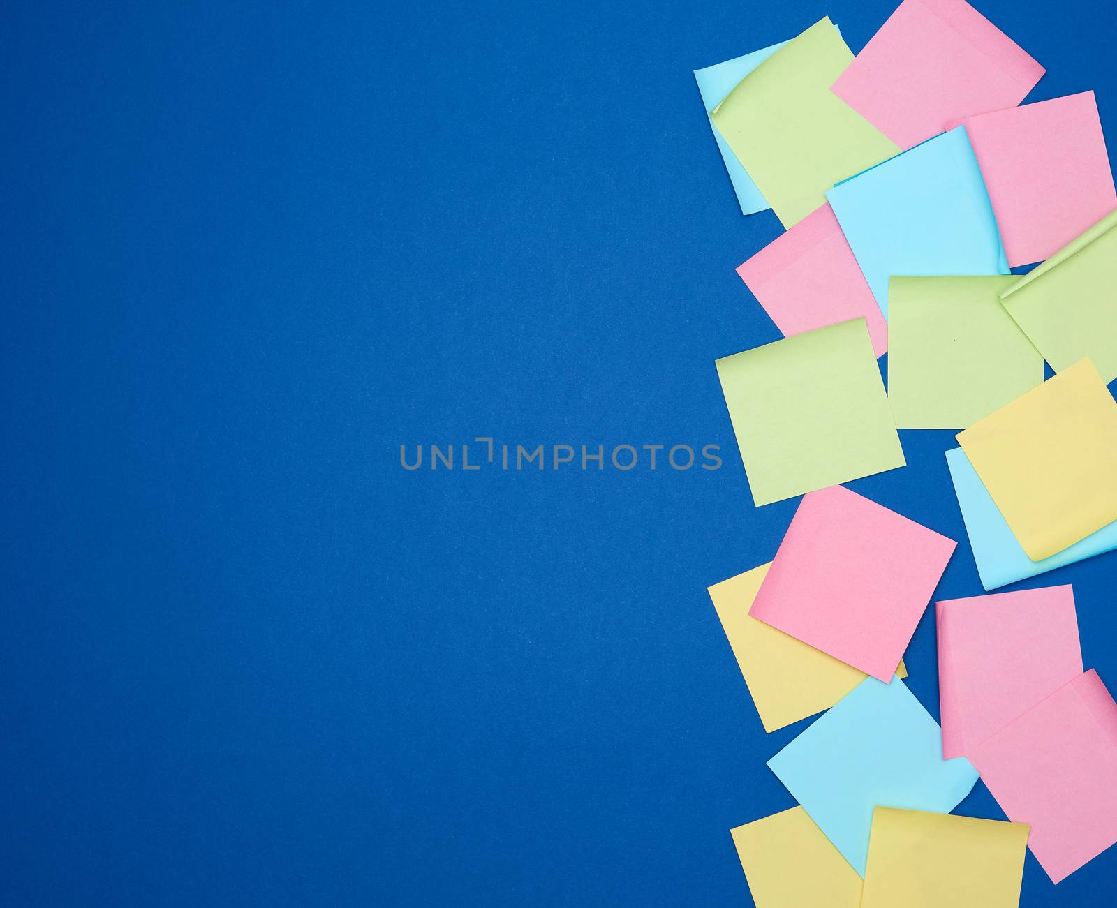 multicolored blank paper stickers of different colors on a dark blue background, copy space